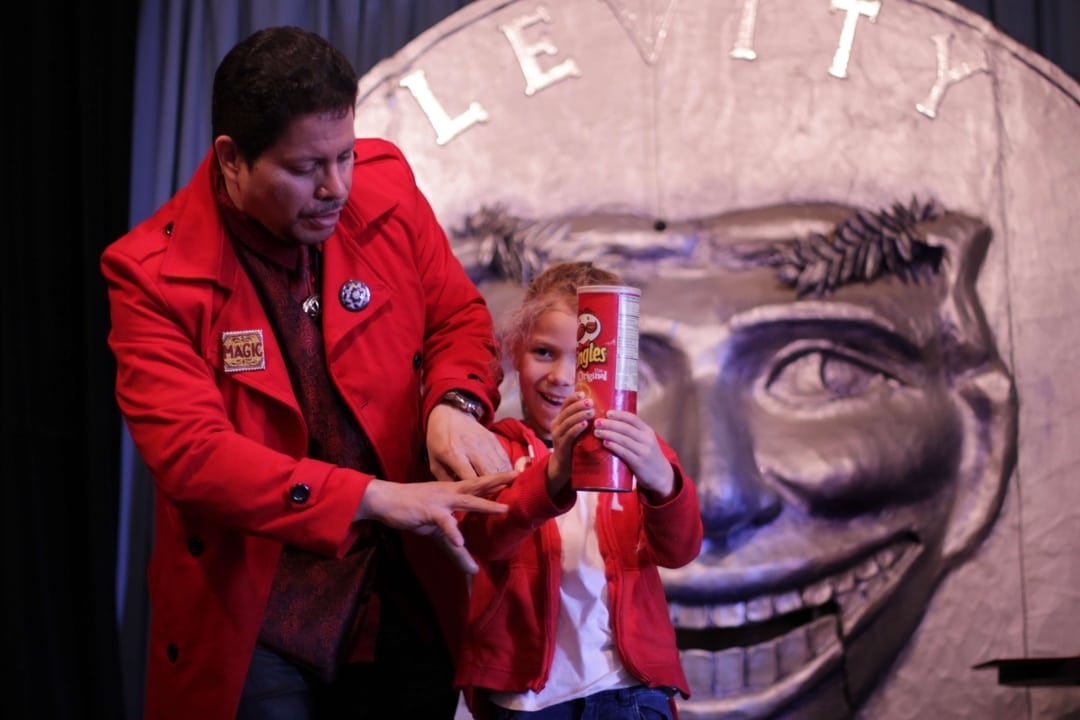 Little girl holds pringles can with magician Dr. S. on stage