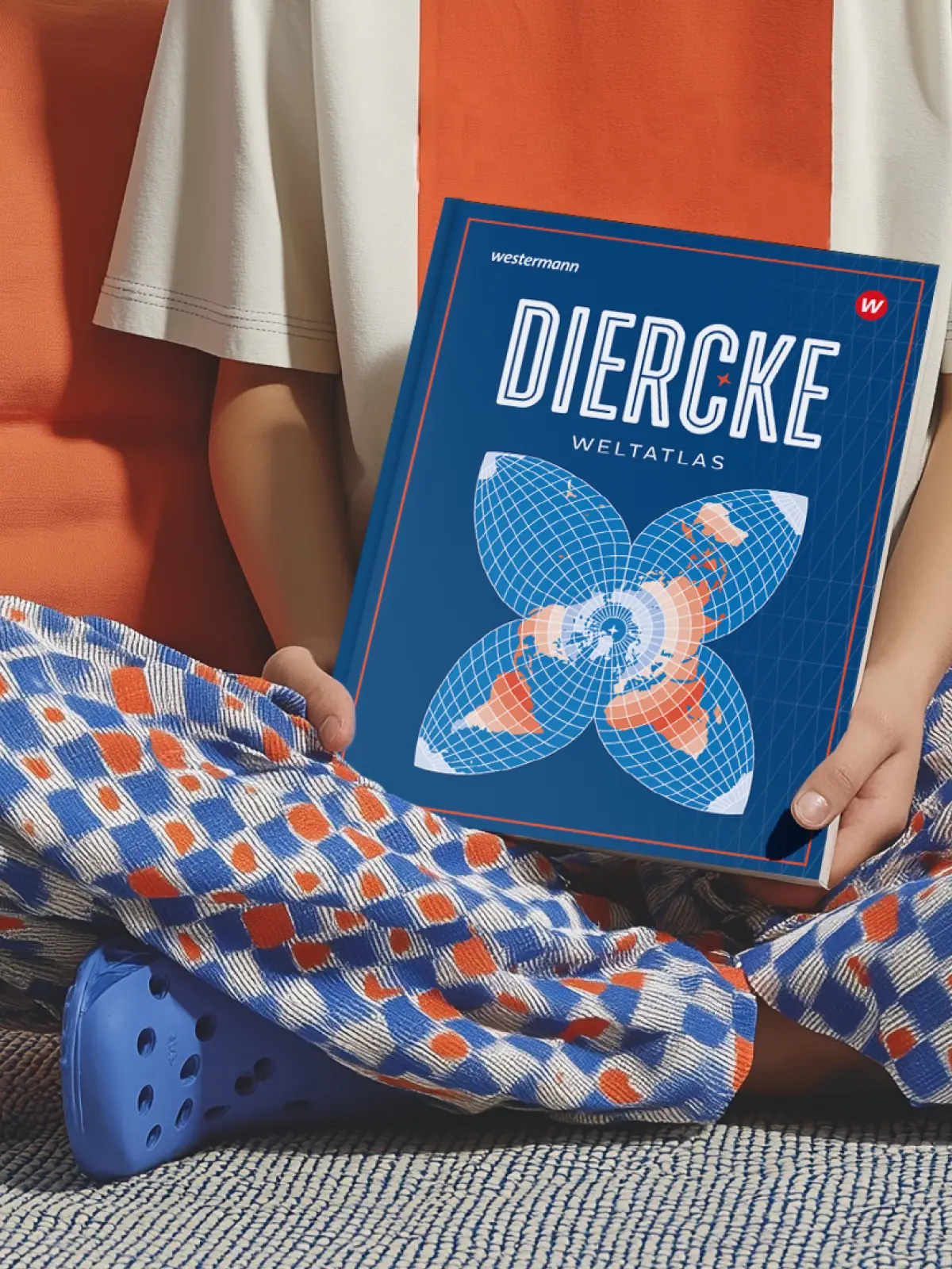Person hält den Diercke Weltatlas