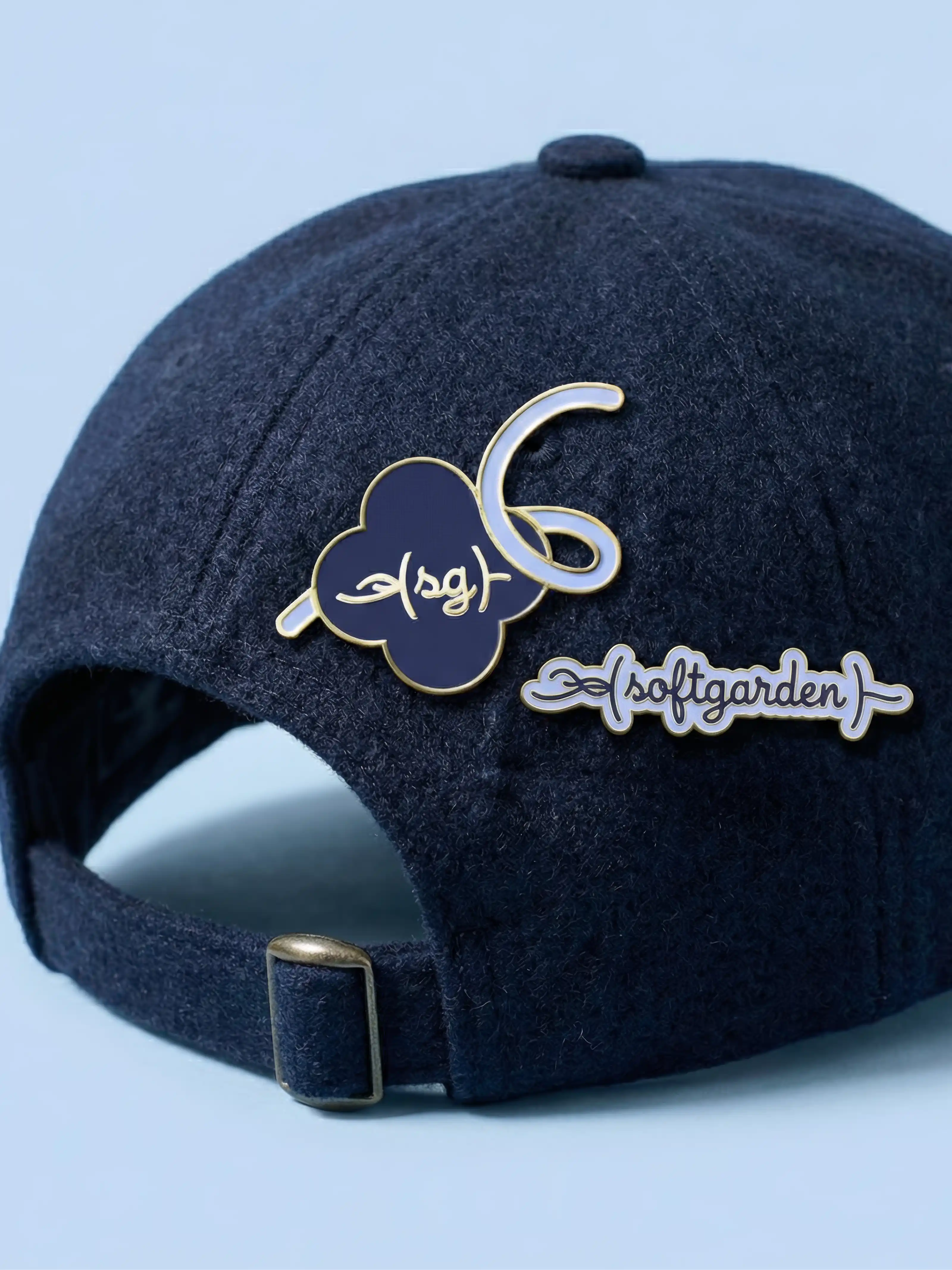 Detailaufnahme von Emaille-Pins mit Marken-Logo auf einer dunkelblauen Basecap als Teil der Corporate Identity.