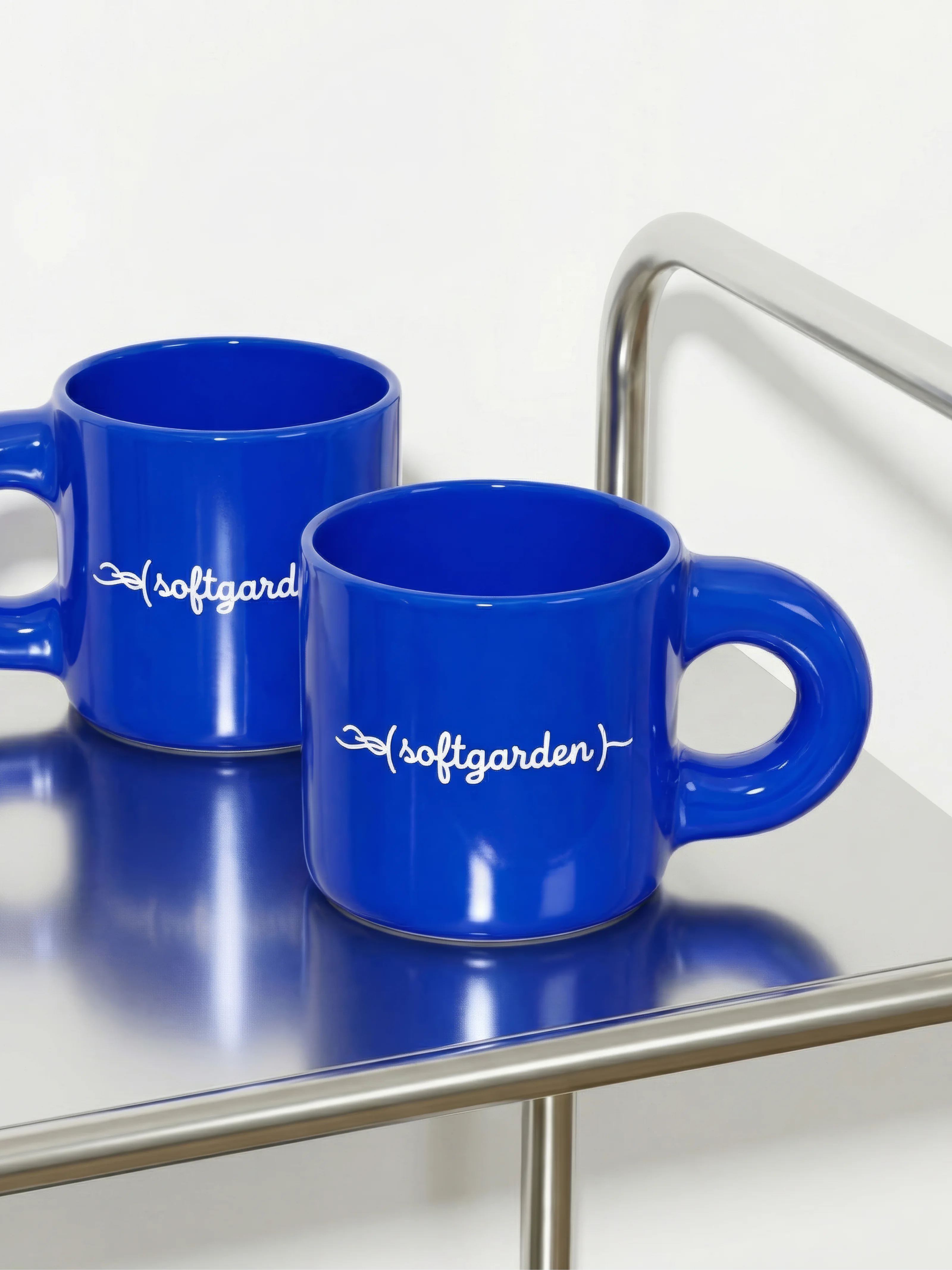 Hochwertige Merchandising-Artikel: Blaue Keramikbecher mit weißem softgarden Logo-Print.