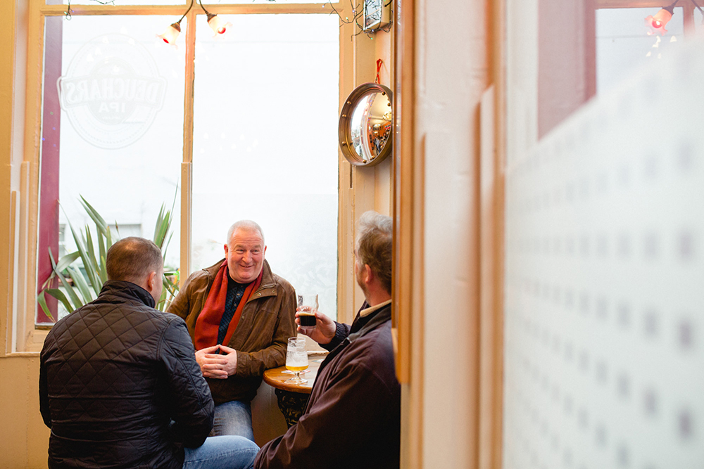 Three old boys enjoy a pint at The Grapes pub in Liverpool 