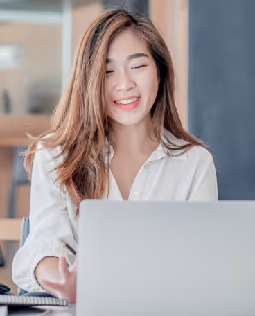 Smiling woman uses a laptop at her desk, representing Formstack’s digital productivity and workflow solutions.