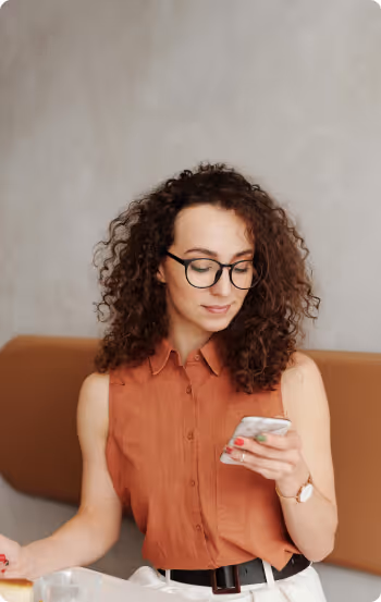 Person with curly hair and glasses wearing an orange sleeveless shirt using a Formstack on a smartphone.