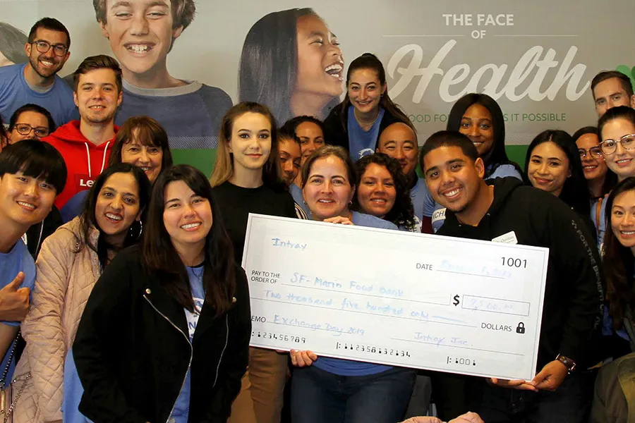 Group of smiling diverse people holding large check for SF-Marin Food Bank donation of $2,500.