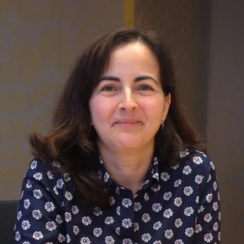 Woman with shoulder-length dark hair wearing a navy shirt with white flower patterns, smiling slightly.