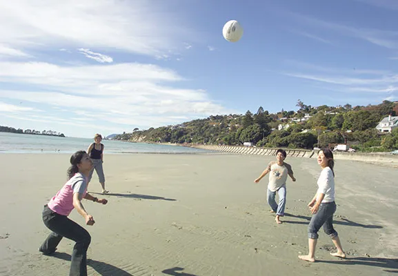 a group of people on the beach throwing a ball