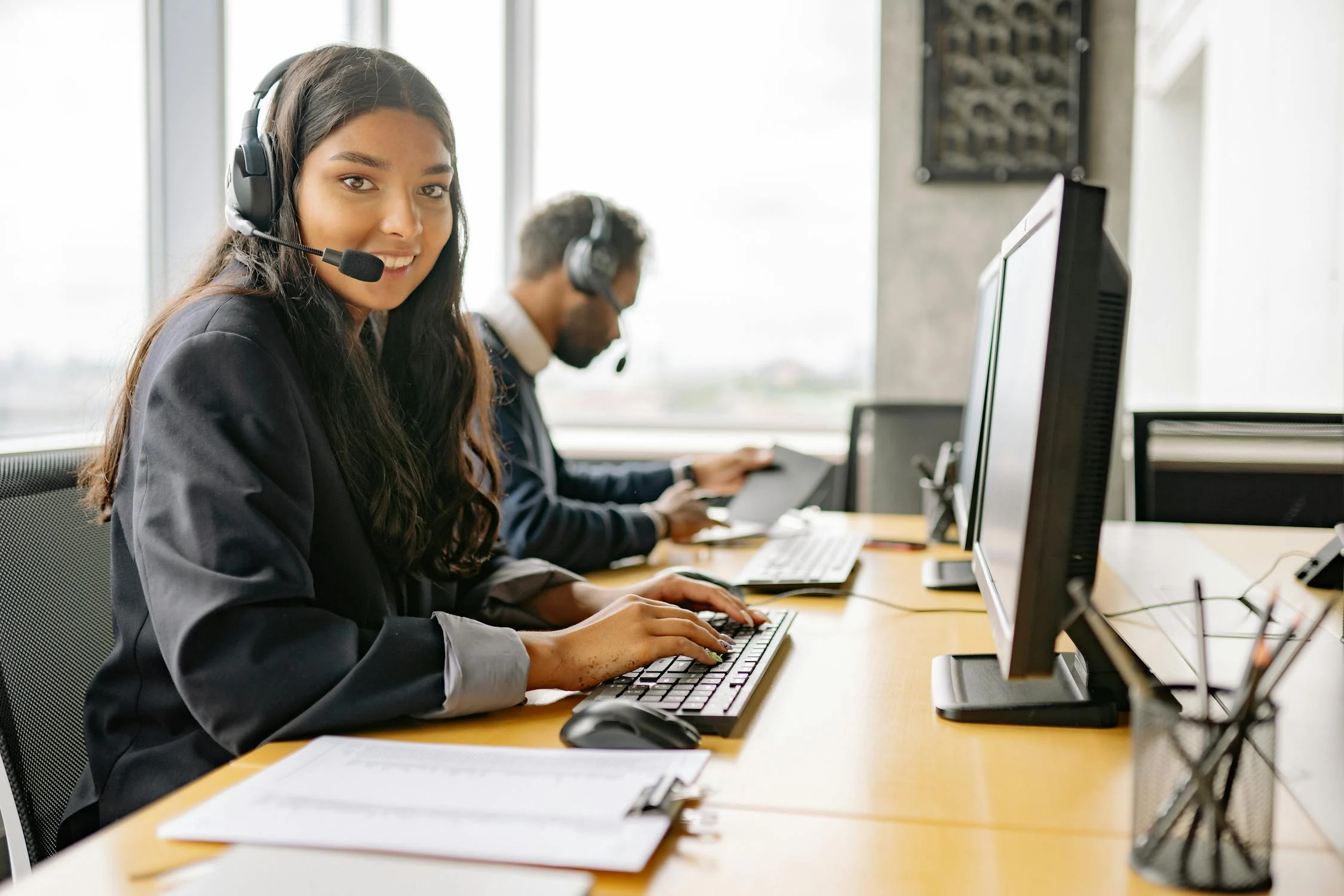 Professional customer service representative with headset smiling in modern office