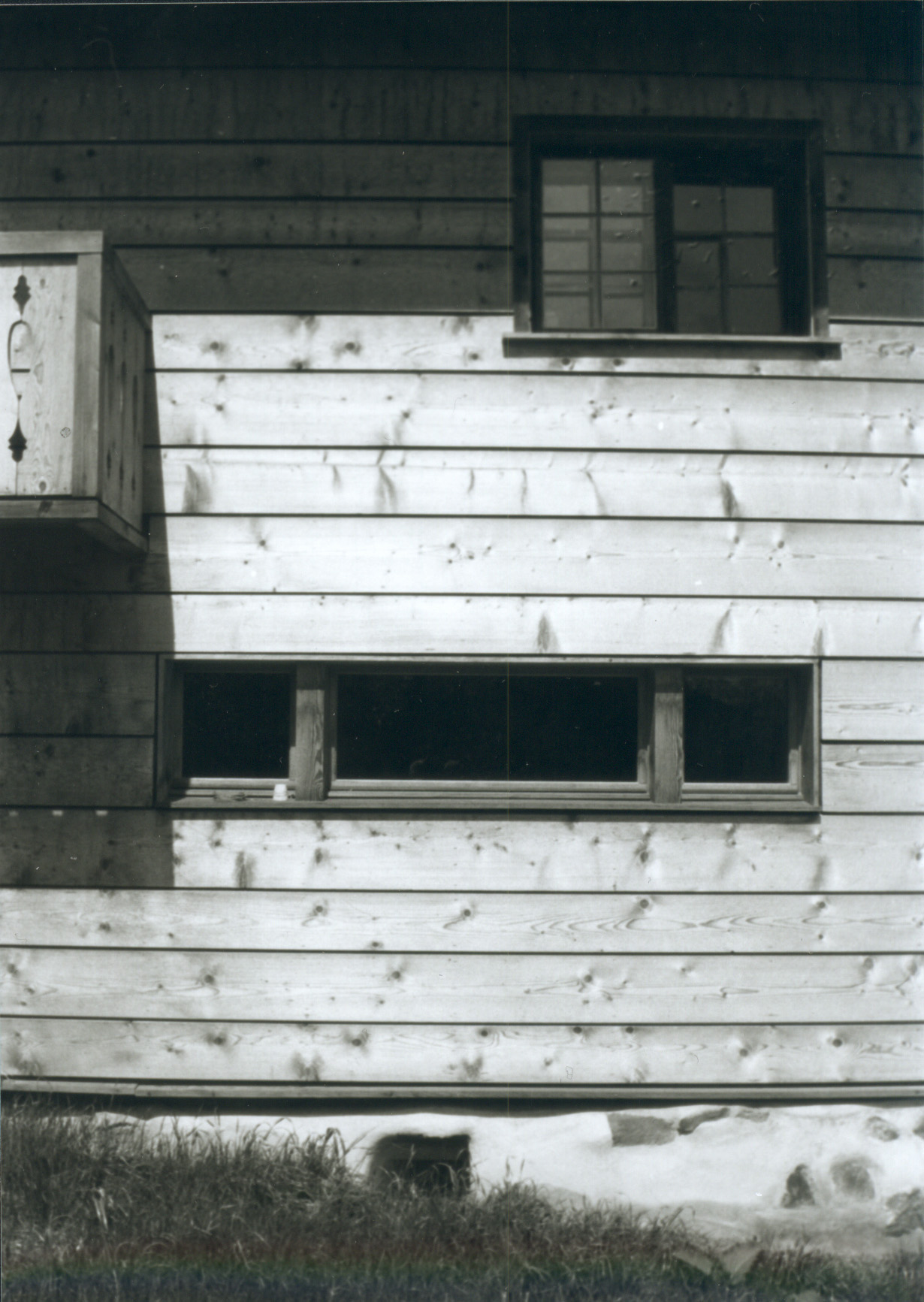 Detail der Holzfassade von Haus Conters mit breitem Fensterband und verziertem Laubengeländer.