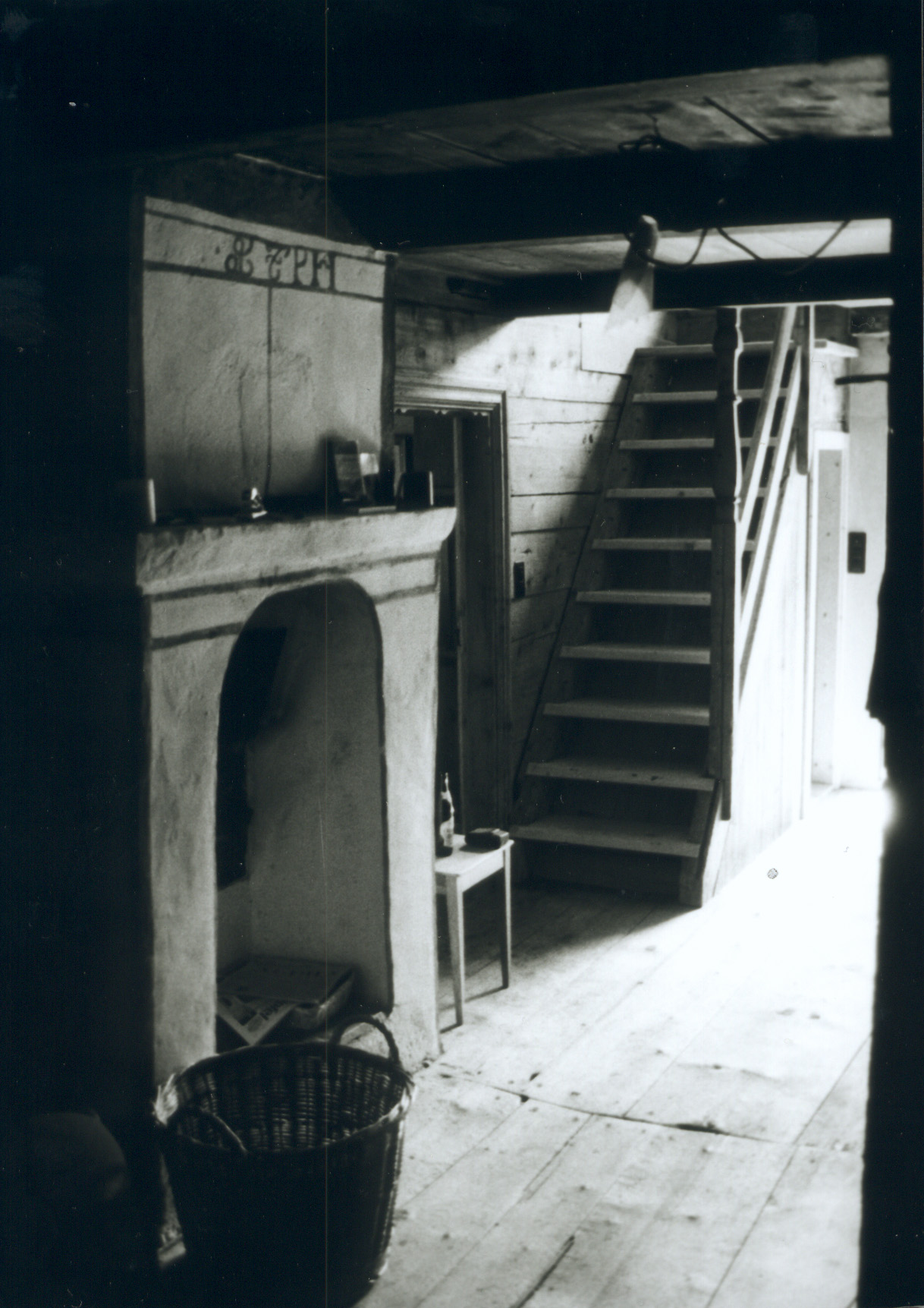 Korridor in Haus Conters mit offener Feuerstelle, Holzboden und Treppe.