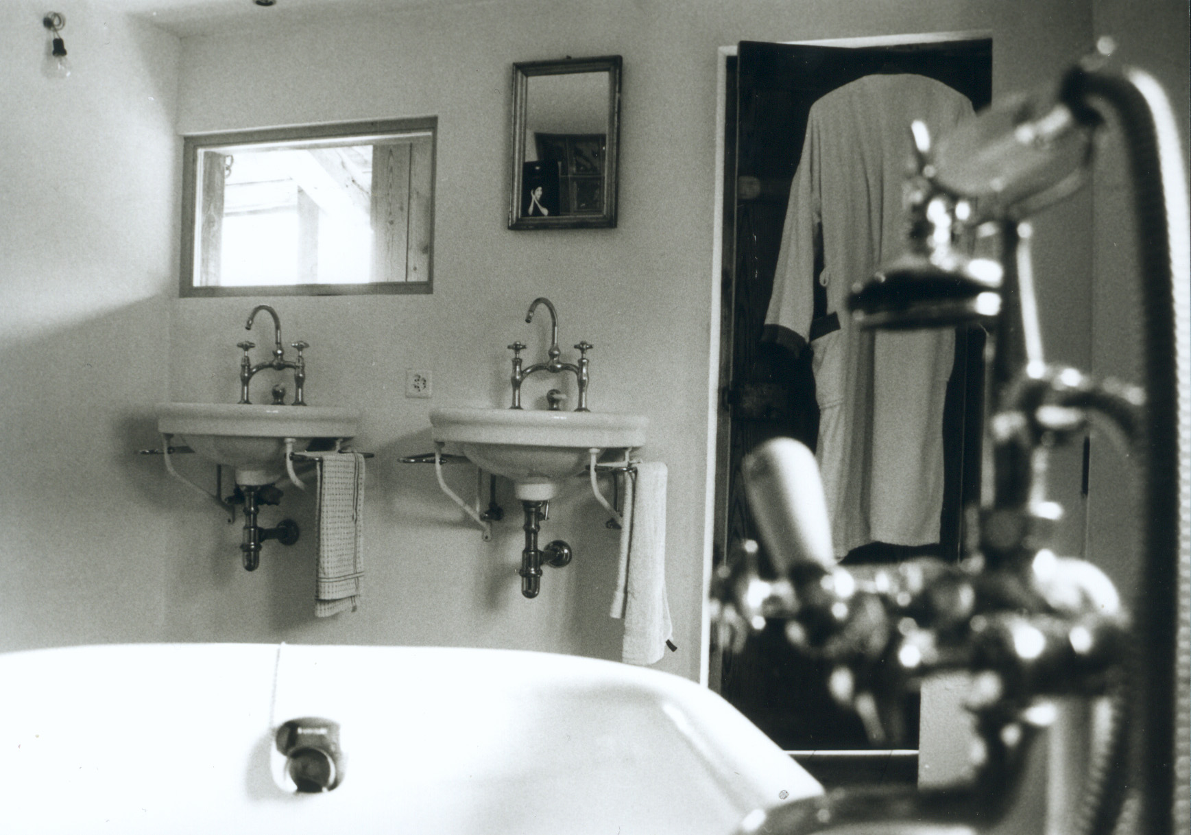 Bad in Haus Conters mit zwei Waschbecken, Spiegeln und Badewanne im Vordergrund.