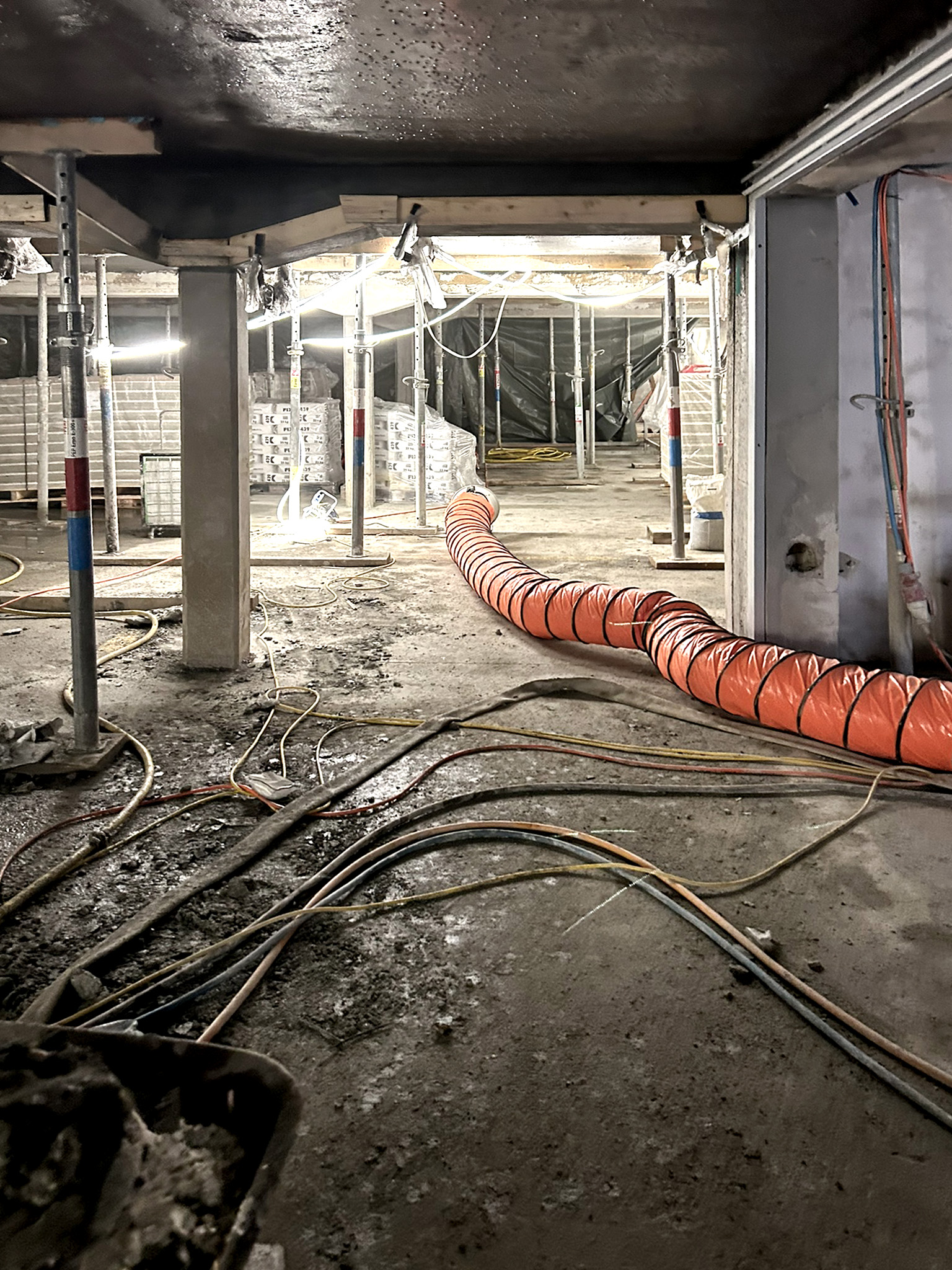 Tiefgarage S22 während der Deckenreprofilierung mit Spritzbeton, Baustützen und einem Lüftungsschlauch.