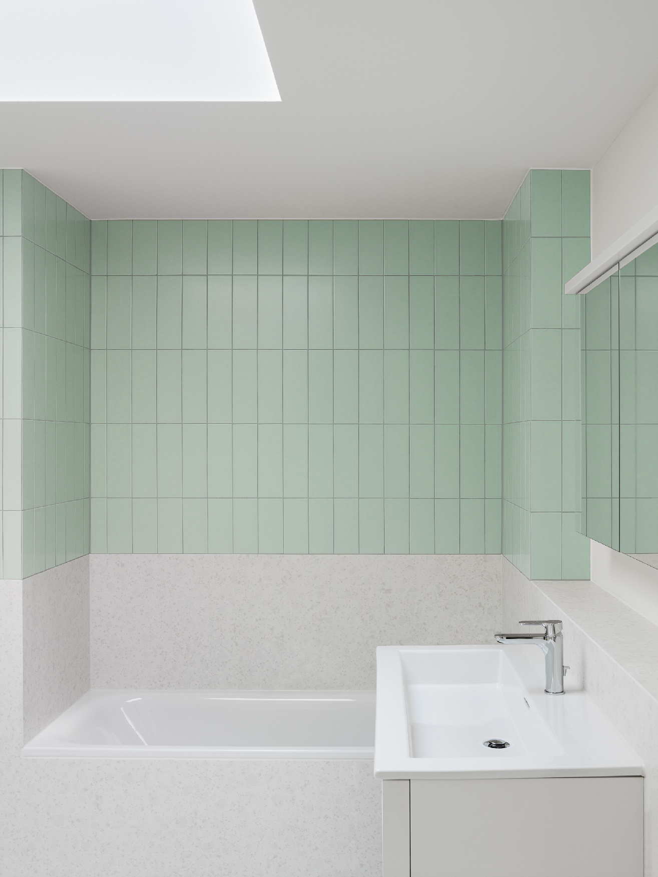 Badezimmer mit hellgrünen Wandfliesen, Badewanne, Waschtisch und Oberlicht an der Wingertlistrasse 16/18.