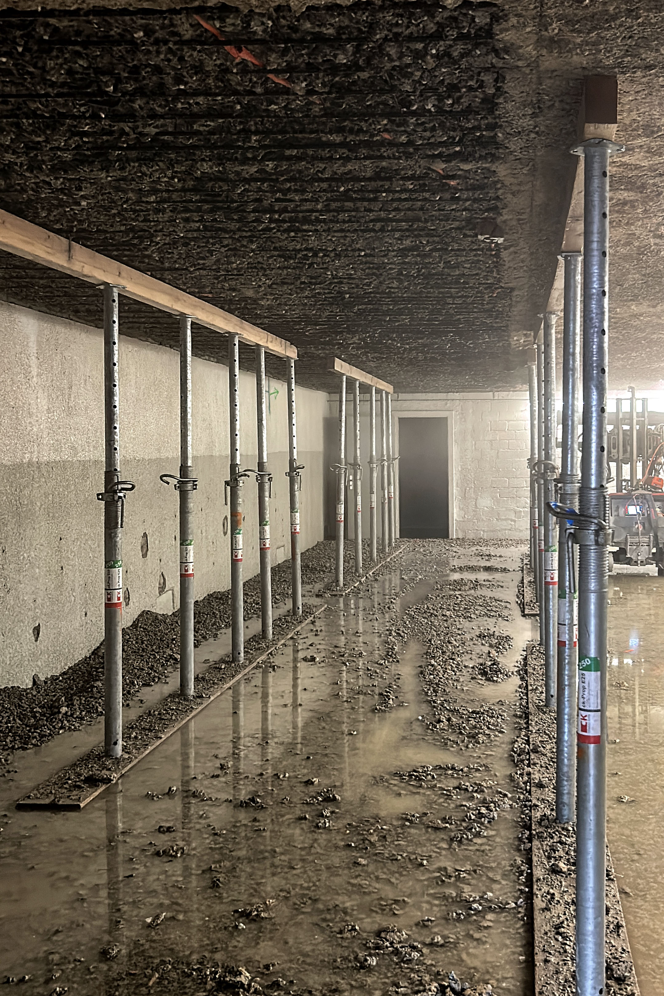 Freigelegte Bewehrung der Tiefgaragendecke nach dem Betonabtrag, gesichert durch provisorische Baustützen.