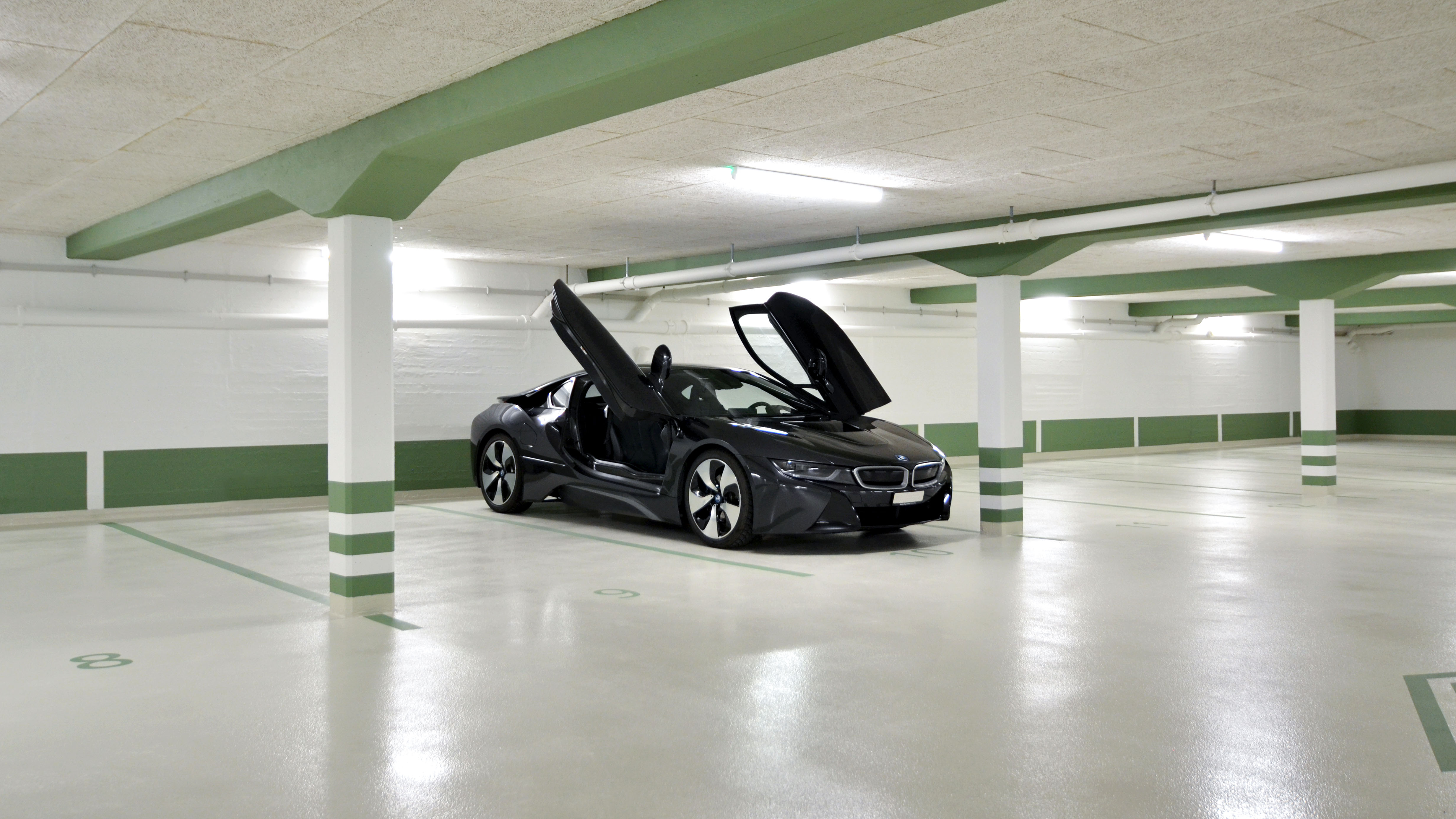 Sanierte Tiefgarage S22 mit grünen Markierungen, hellen Oberflächen und einem geparkten Sportwagen.