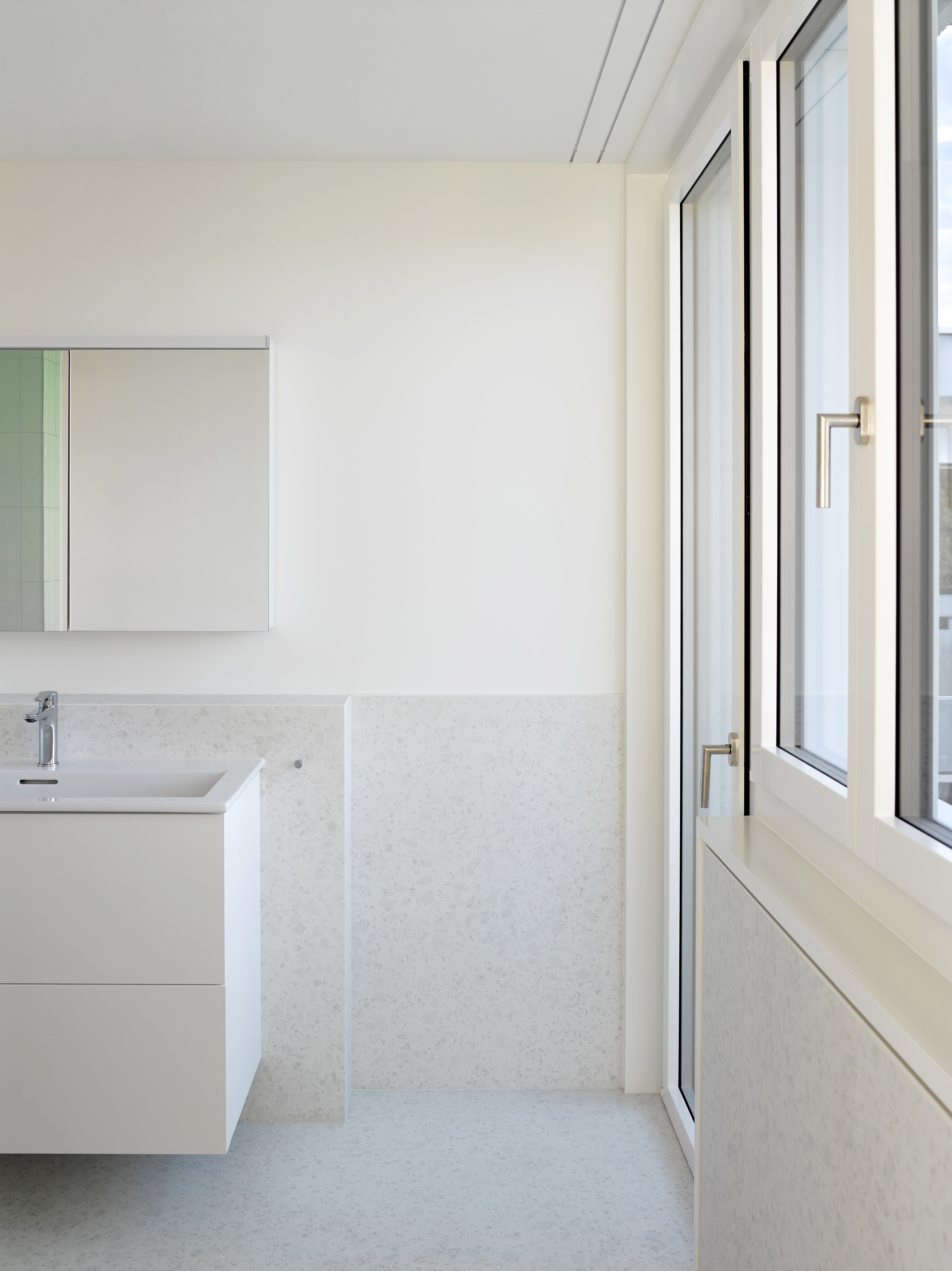 Helles Badezimmer mit Waschtisch, Spiegelschrank und raumhohem Fenster.