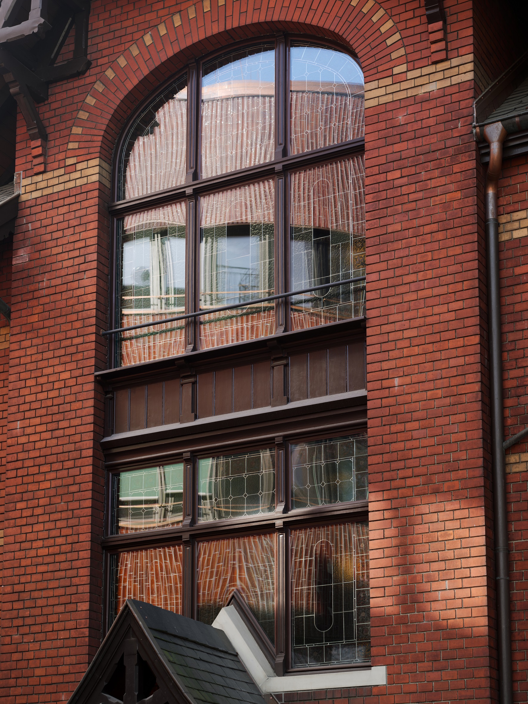 Der Ergänzungsbau spiegelt sich im hohen, bleiverglasten Bogenfenster der Villa Lindeneck.