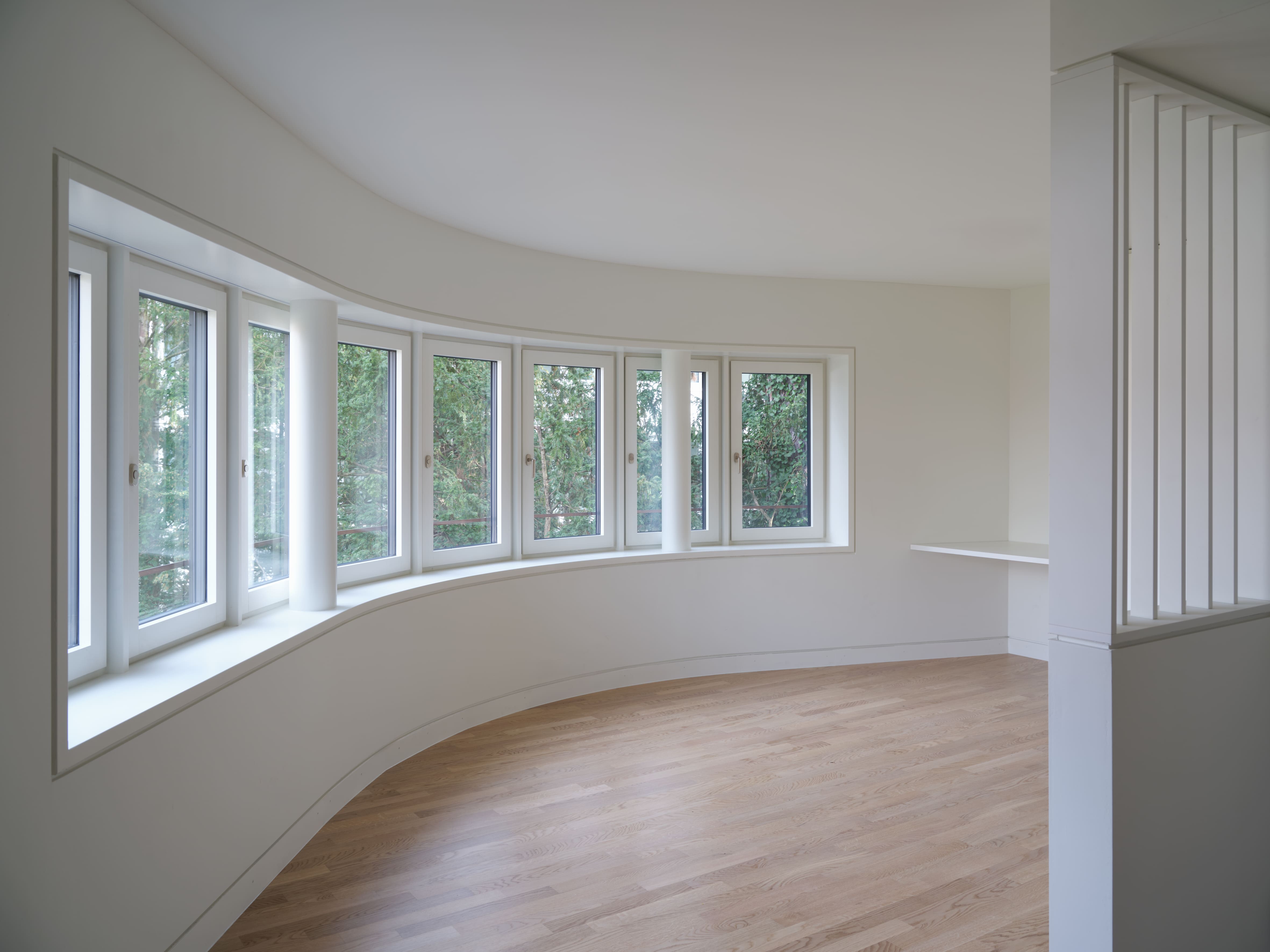 Heller Praxisraum im Ergänzungsbau Lindeneck mit gerundeter Fensterfront und Holzboden.
