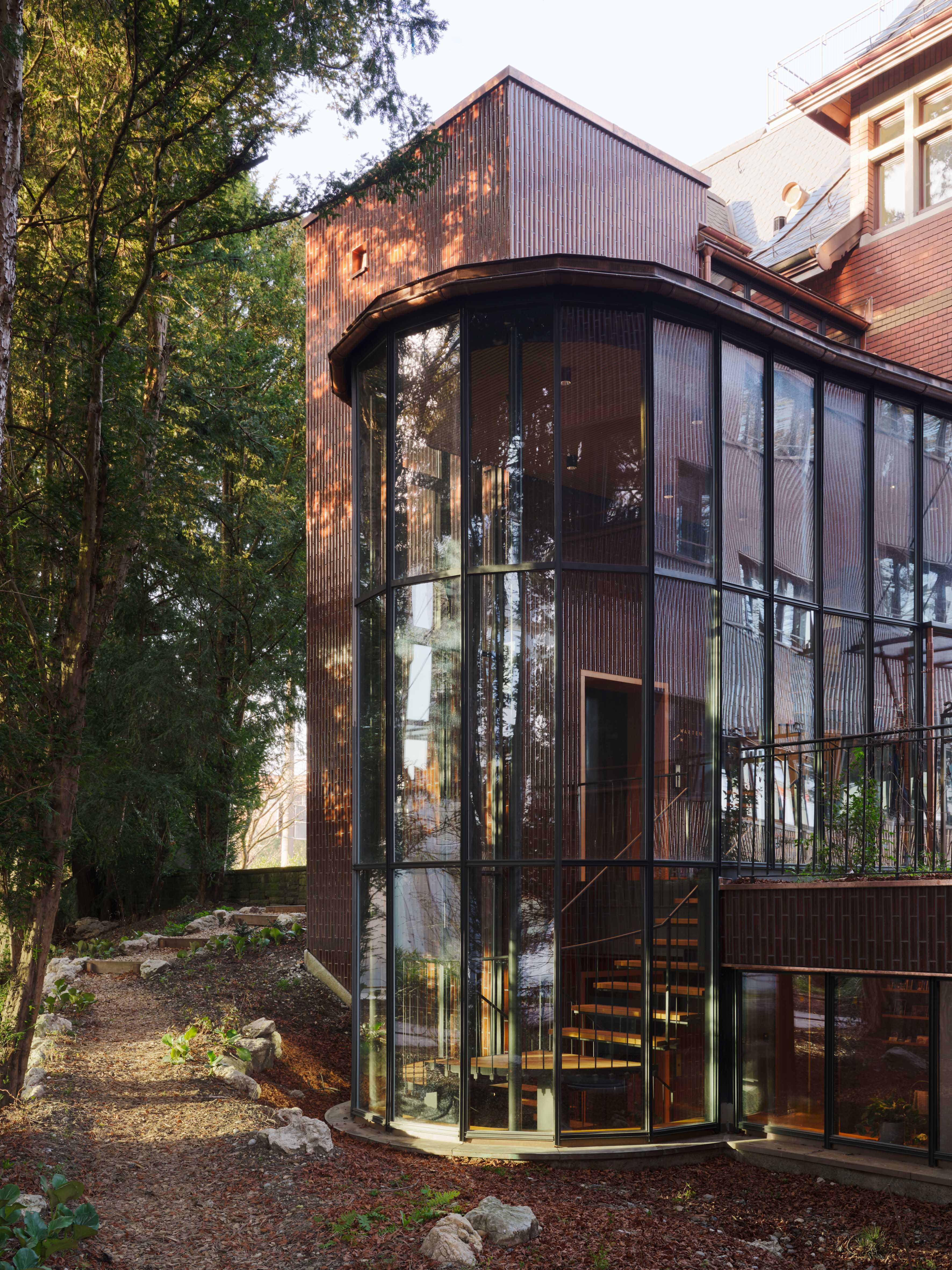 Verglaster Verbindungsbau an der Villa Lindeneck mit sichtbarer Treppe und Gartenweg.