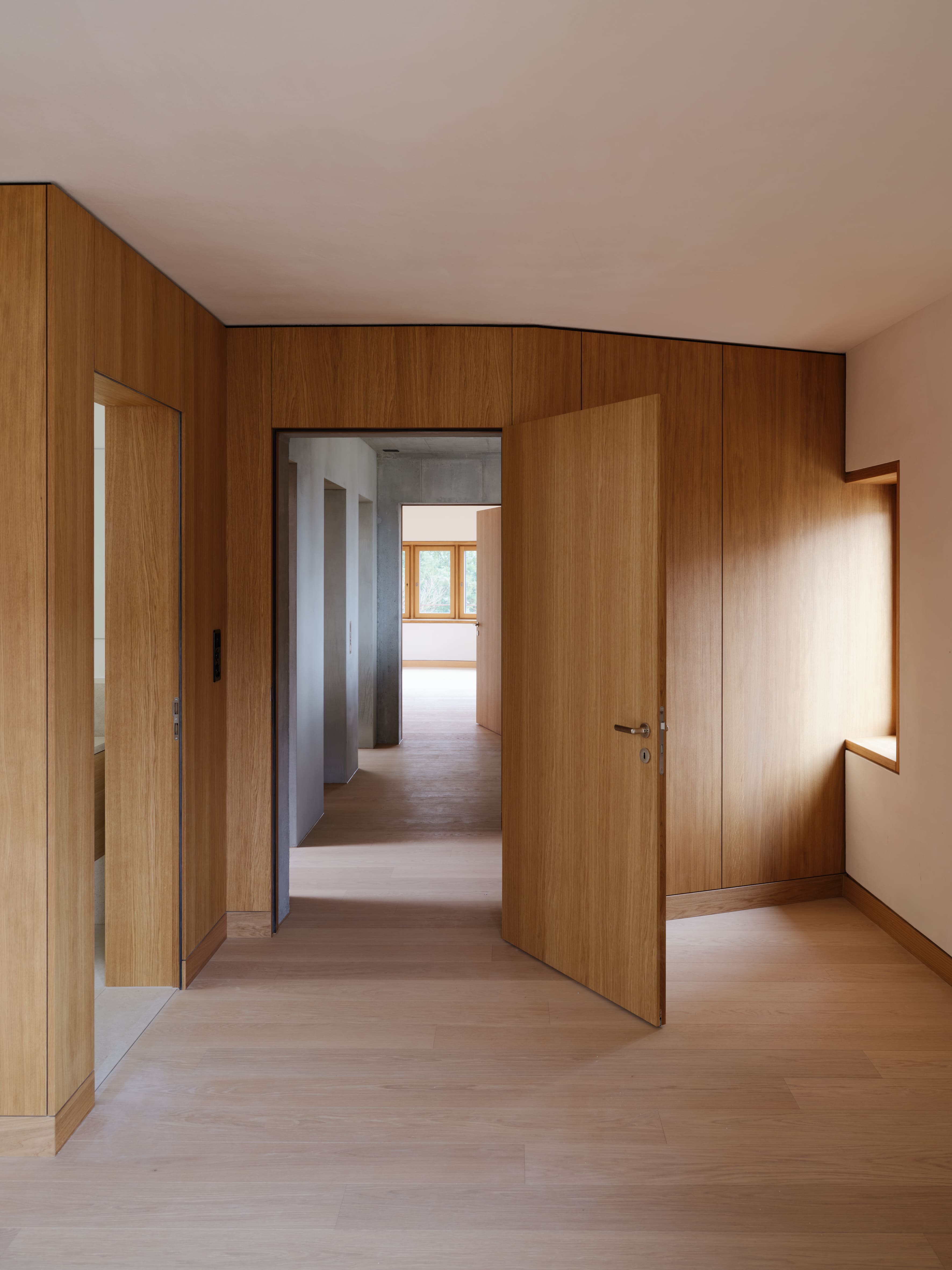 Holzverkleideter Raum der Stadtwohnung im Lindeneck mit geöffneter Tür und Durchblick in weitere Räume.