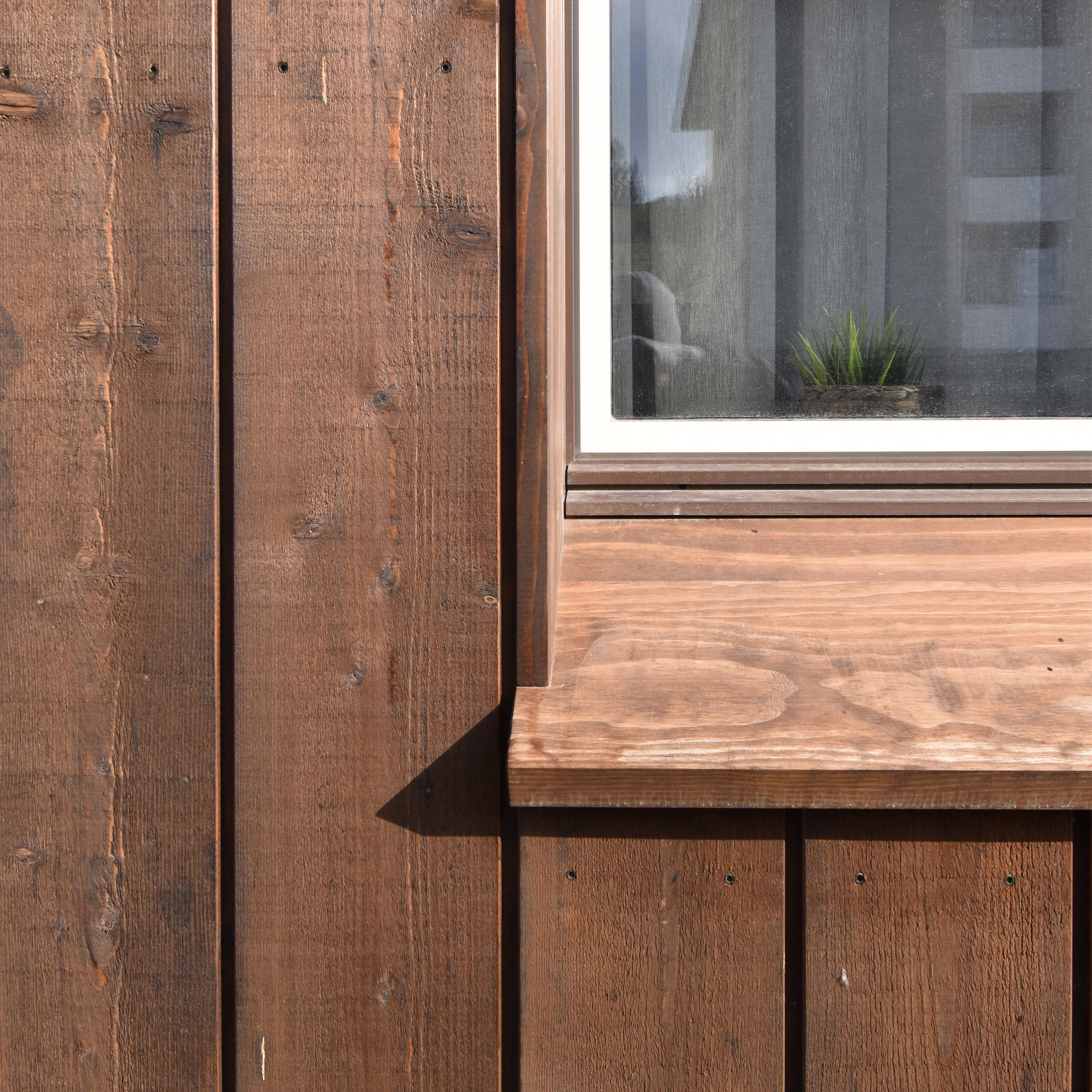 Detail der Holzfassade der Wohnanlage Grünmatt mit Fenster und breiter hölzerner Fensterbank.