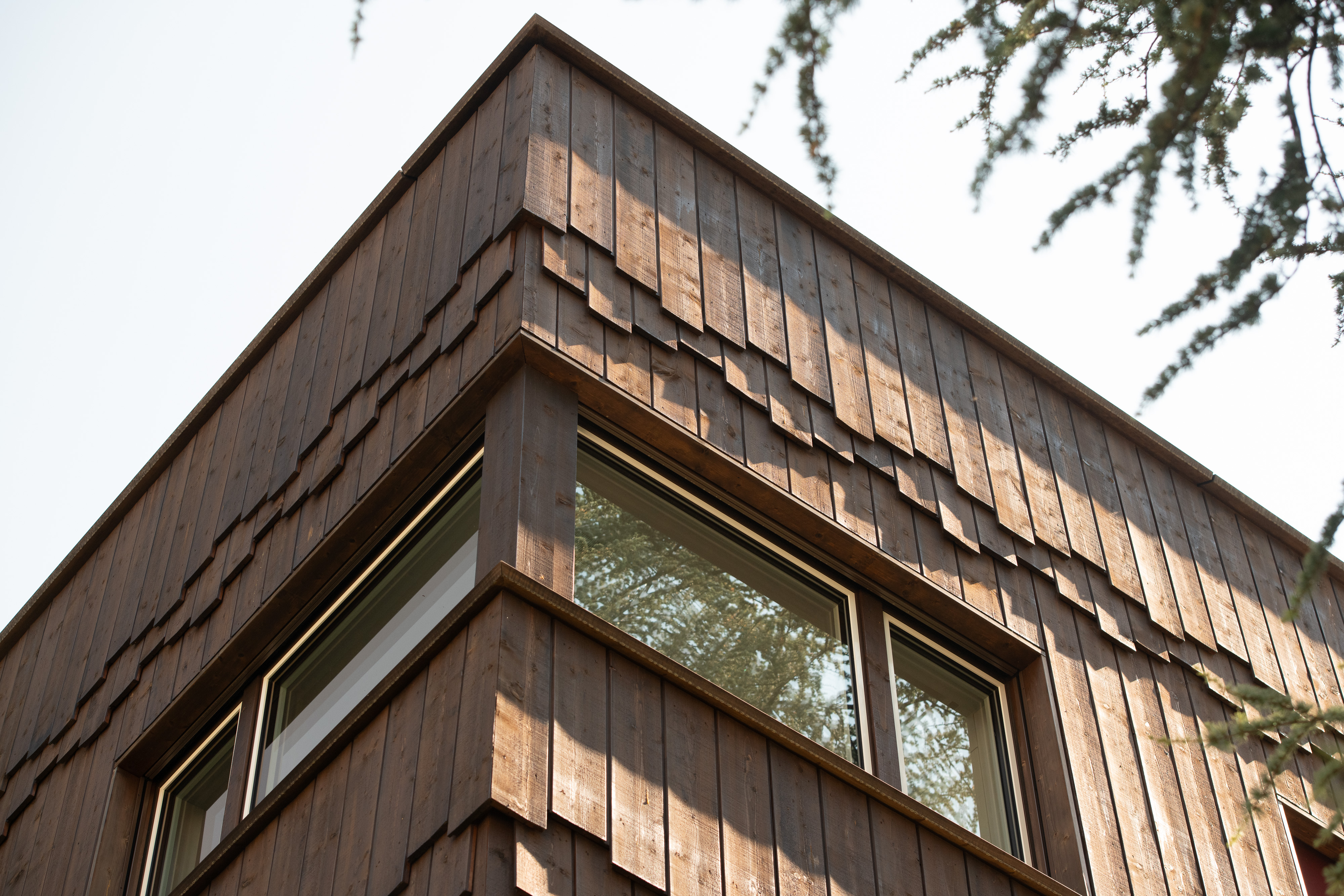 Gebäudeecke der Wohnanlage Grünmatt mit überlappender Holzschalung und Eckfenster.