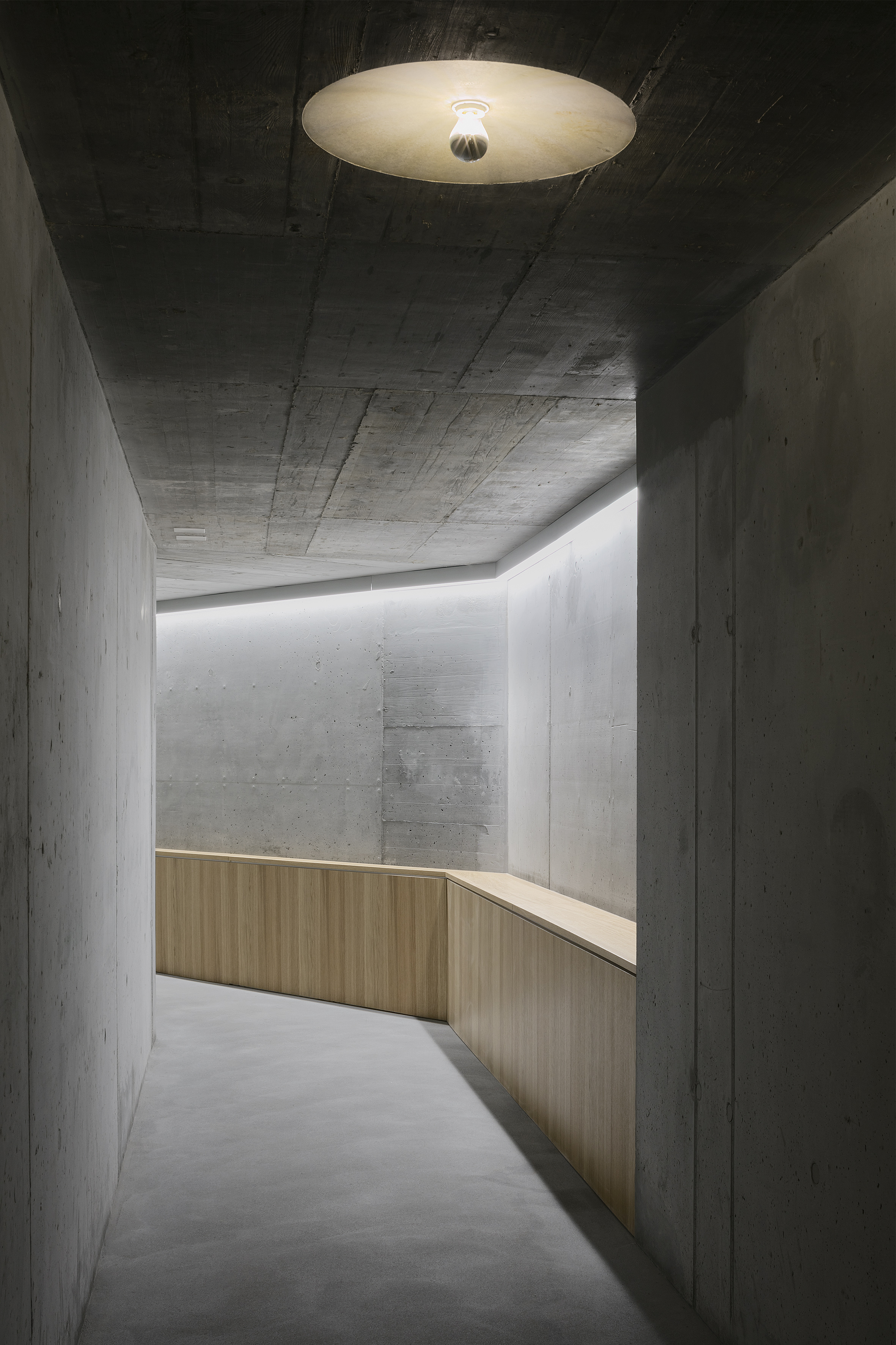Verbindungsgang zwischen Haus A und C der Wohnanlage Grünmatt mit Sichtbeton und Holzgeländer.