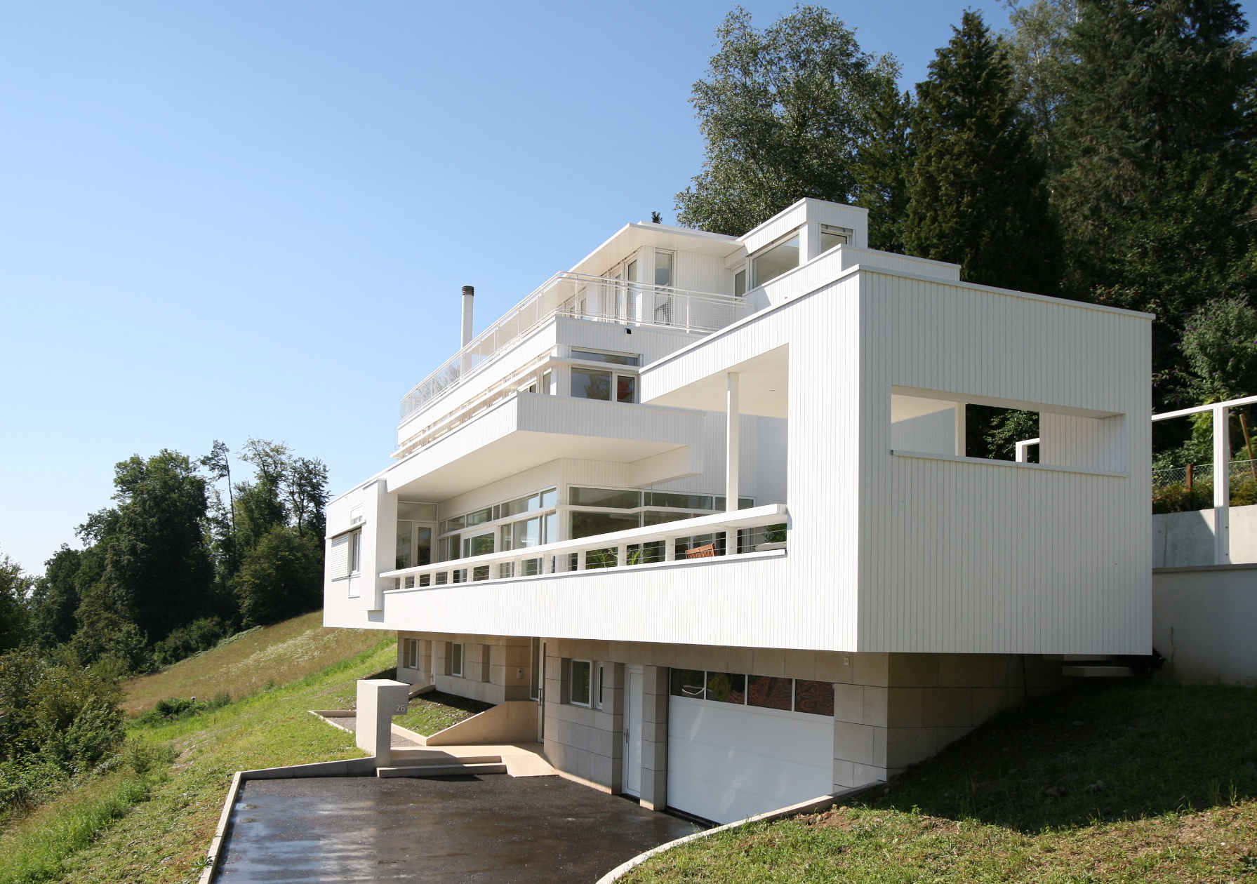 Zufahrt, Garage und Eingang von Haus Trottenweg unter der weissen Balkonfront.