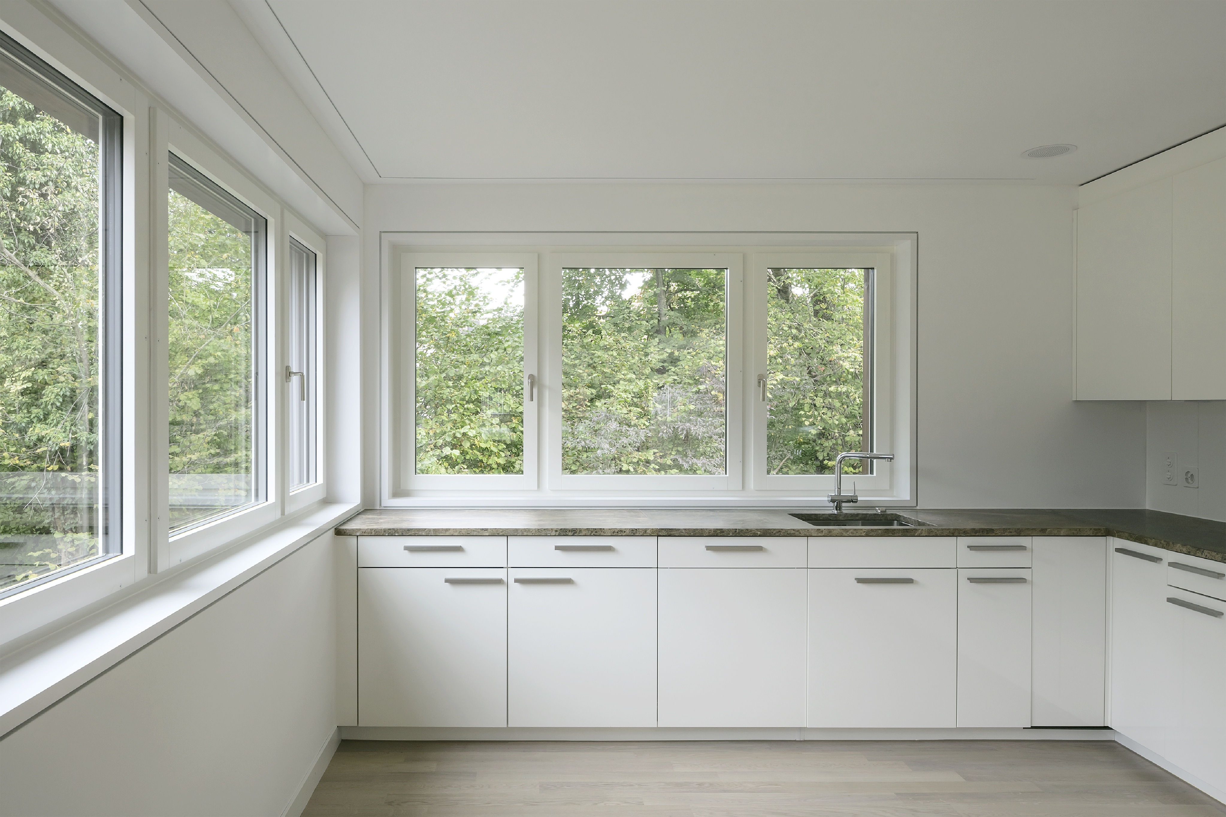 Helle Küche in Haus B der Wohnanlage Grünmatt mit umlaufenden Fenstern und Blick ins Grüne.