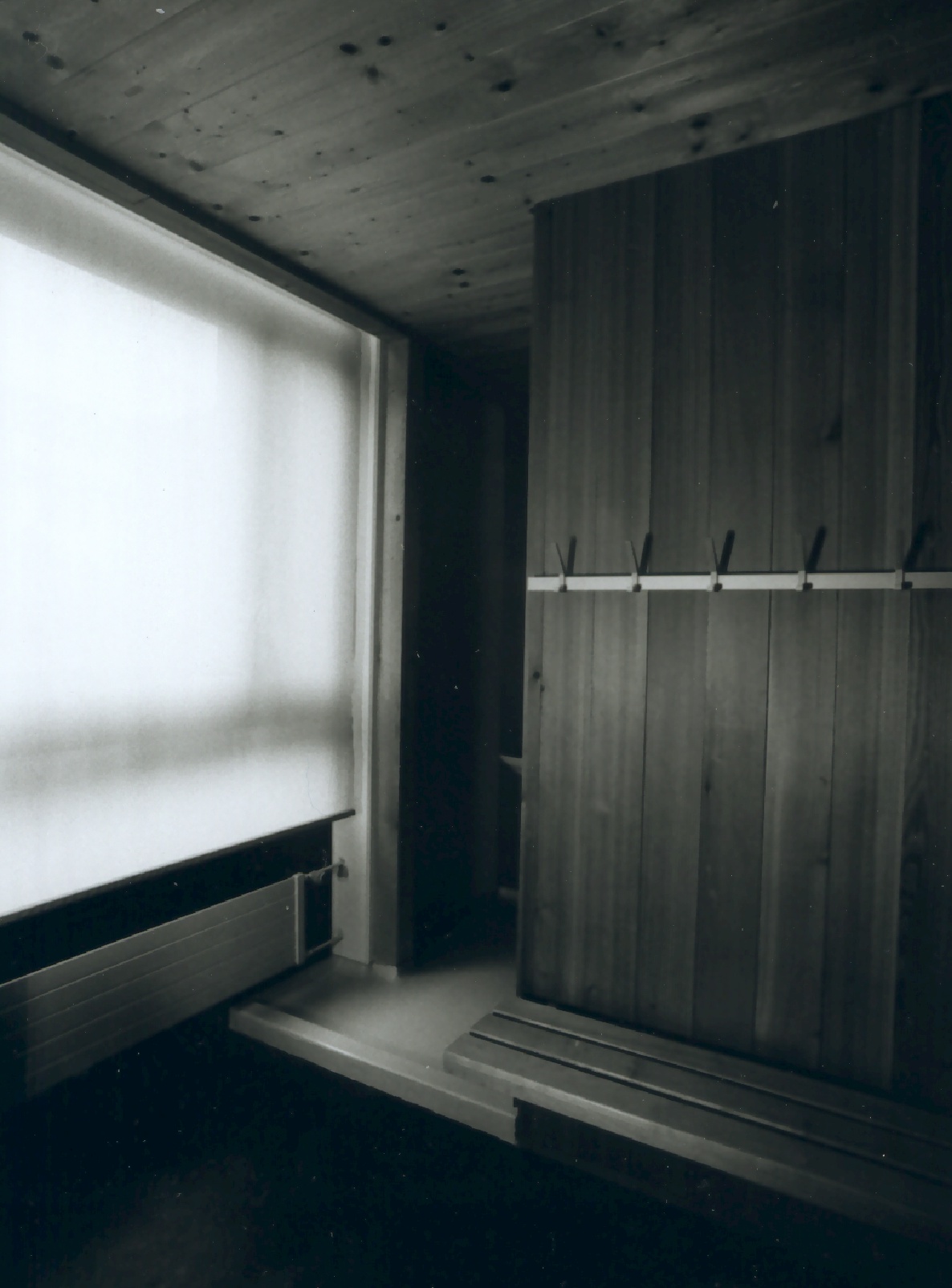 Garderobe im Aikido-Dojo mit Holzbank, Kleiderhaken und transluzentem Fenster.