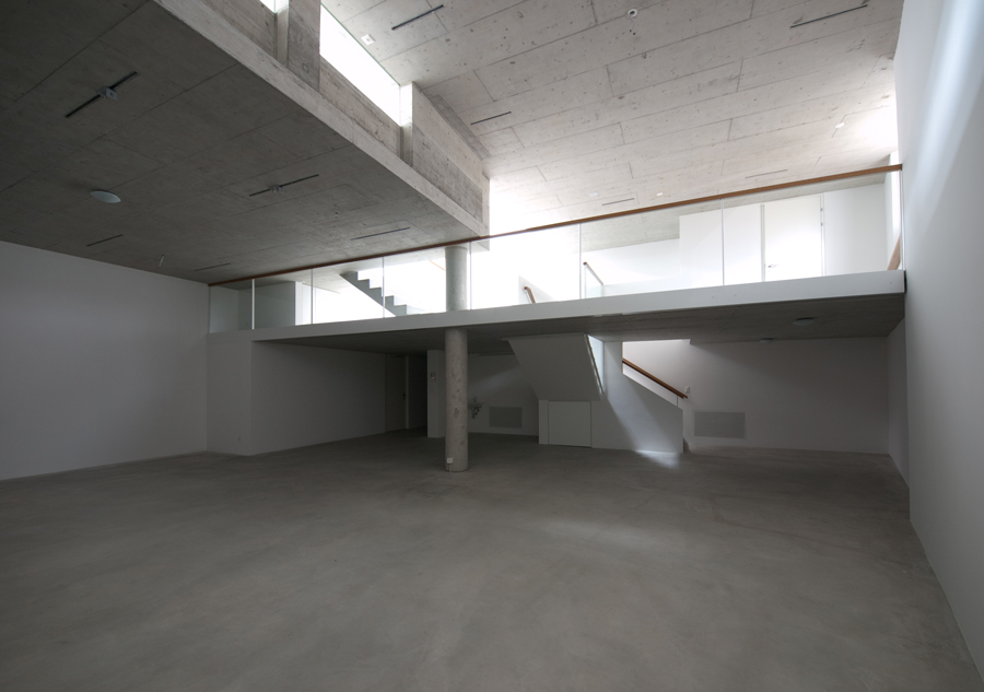 Untergeschoss der Galerie T77 mit doppelter Raumhöhe, Betonstützen und Galerieebene.