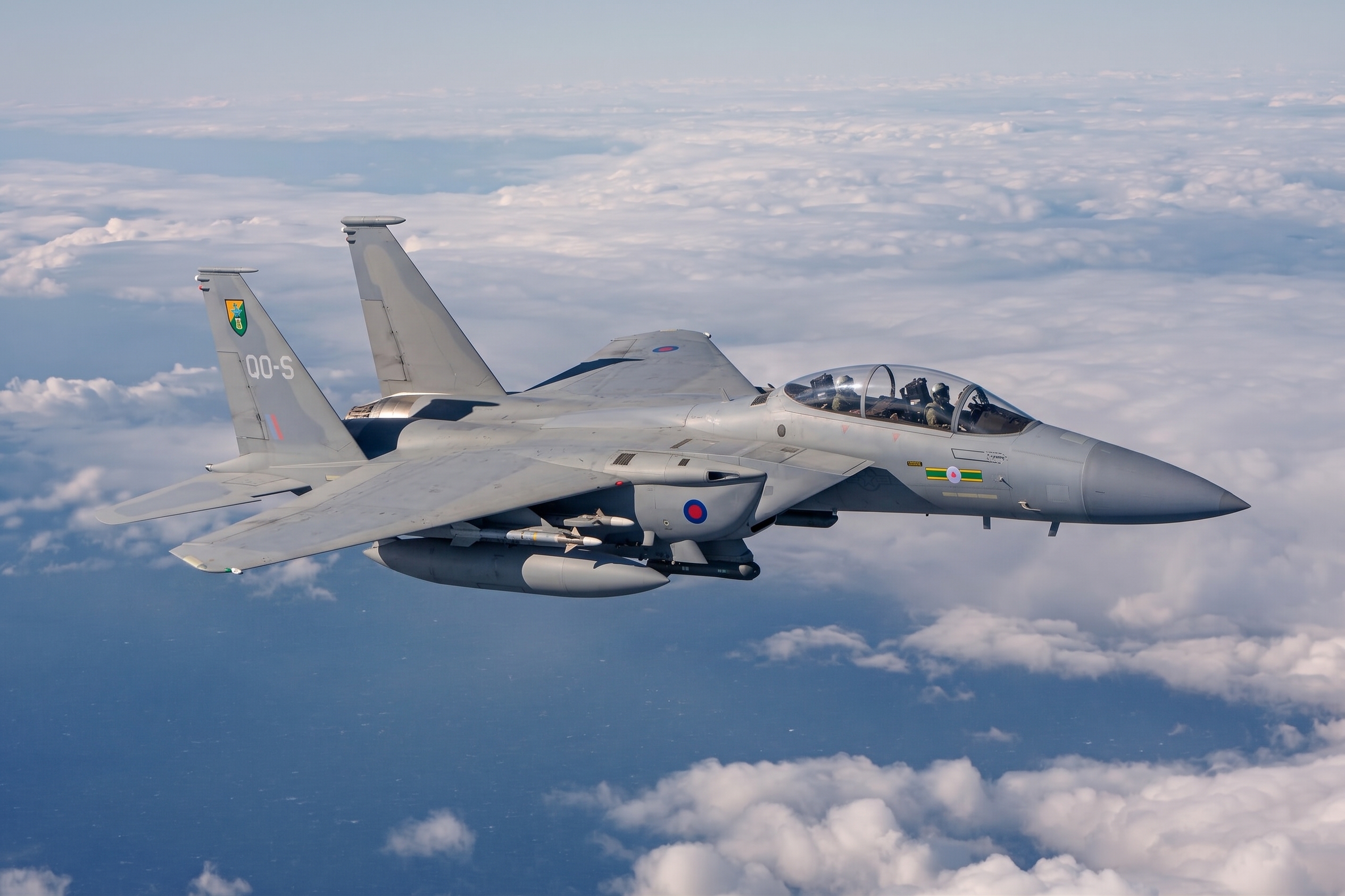 Fighter jet banking against a blue sky above the clouds