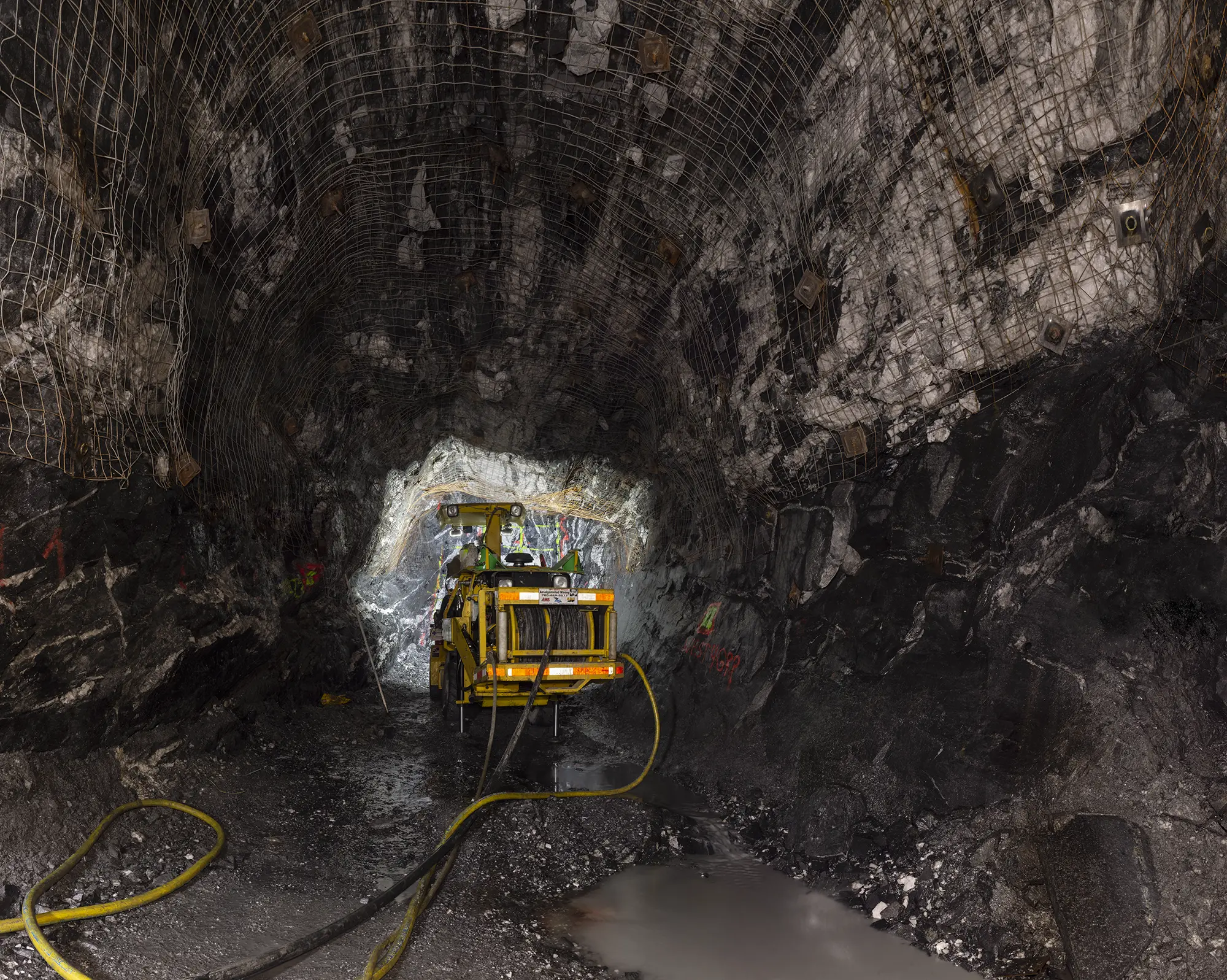 Large format photo of a blast hole drilling rig 275m underground at a gold mine.