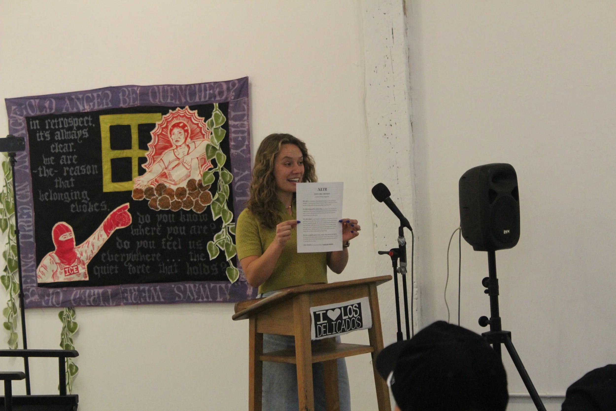 Reader holding a printed page beside a microphone.