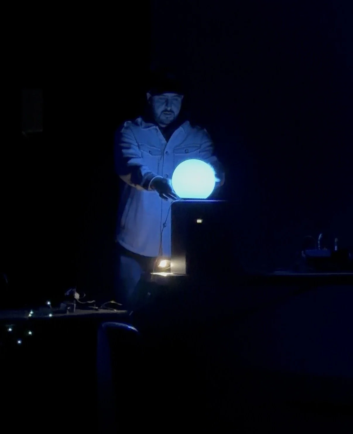 A participant holds a glowing sphere in a dark room.