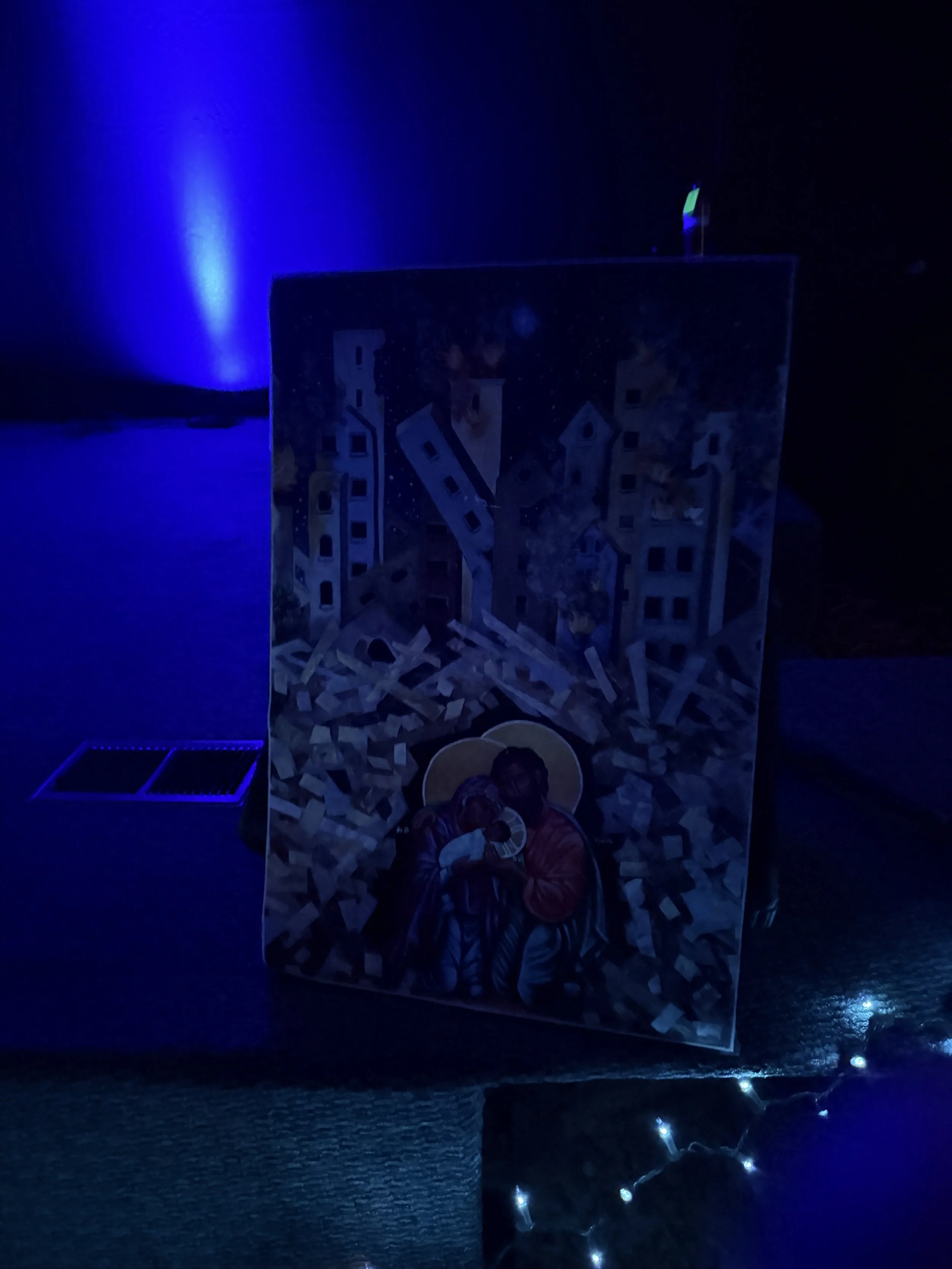 Religious artwork displayed beside string lights.