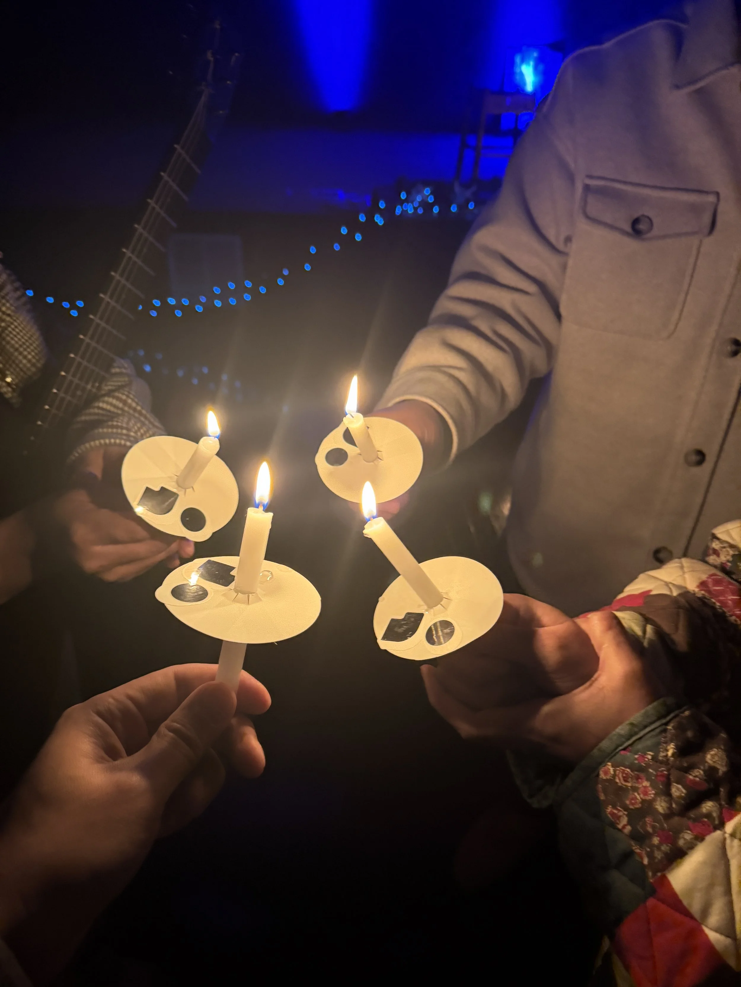 Participants hold small lit candles together.