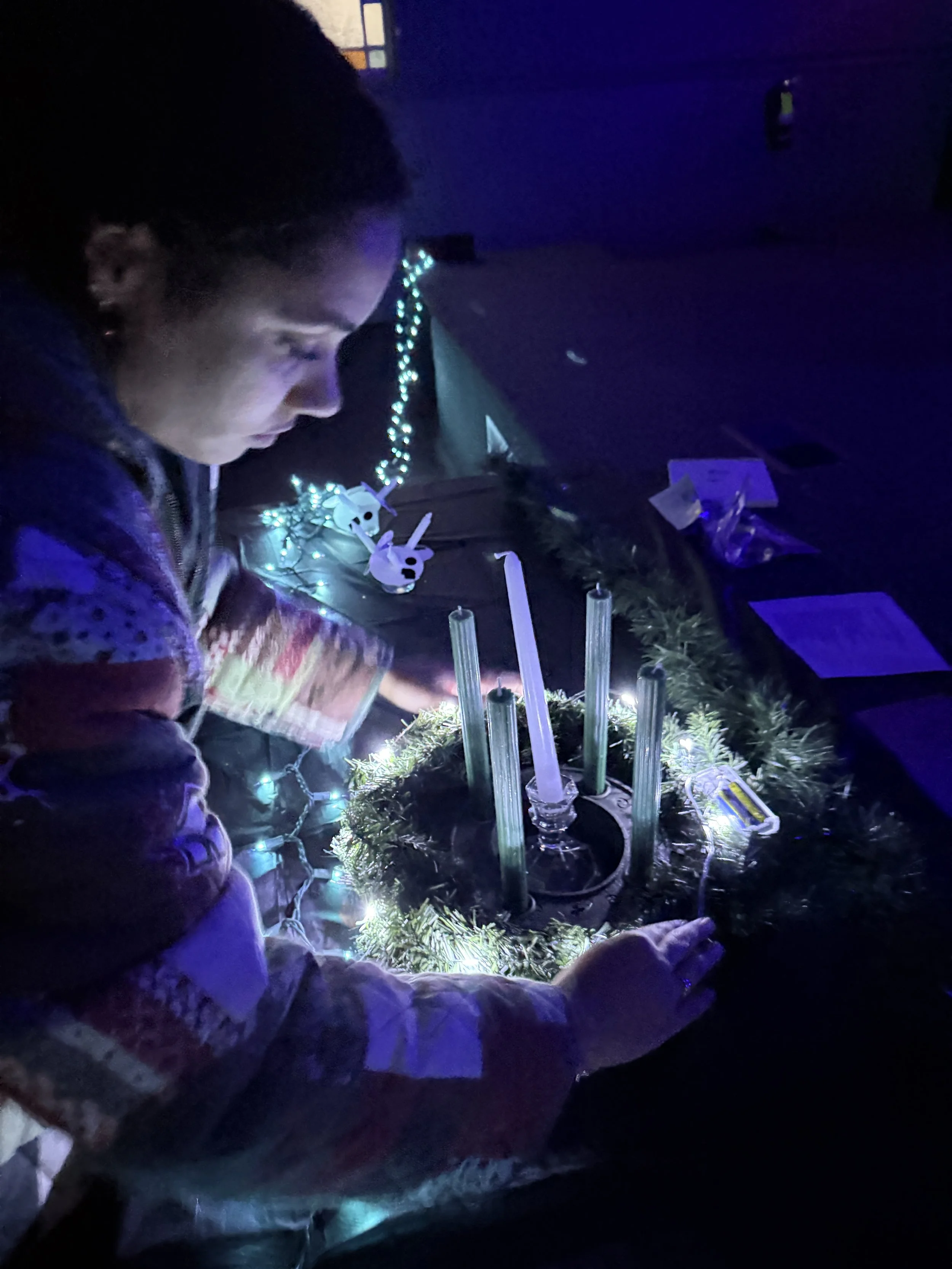 A participant lights candles in an Advent wreath.