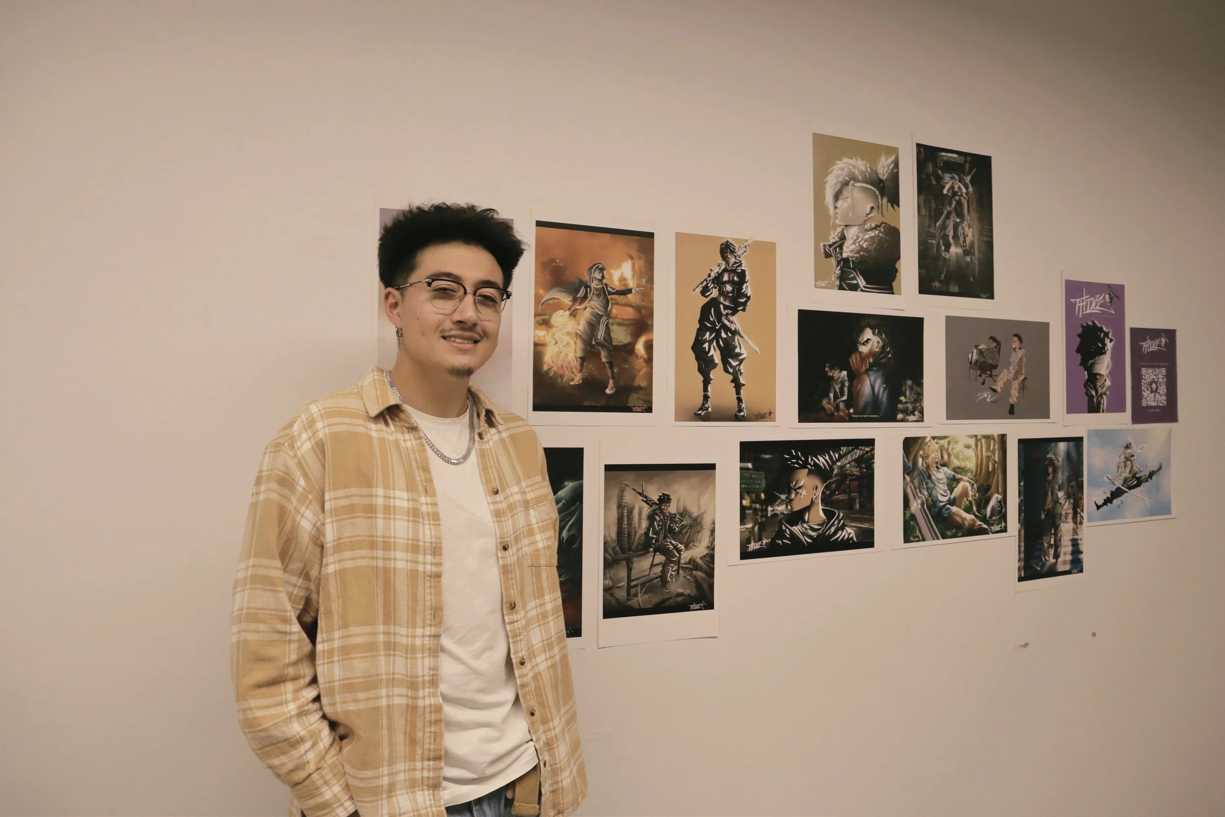 An artist stands beside a display of photographic work.