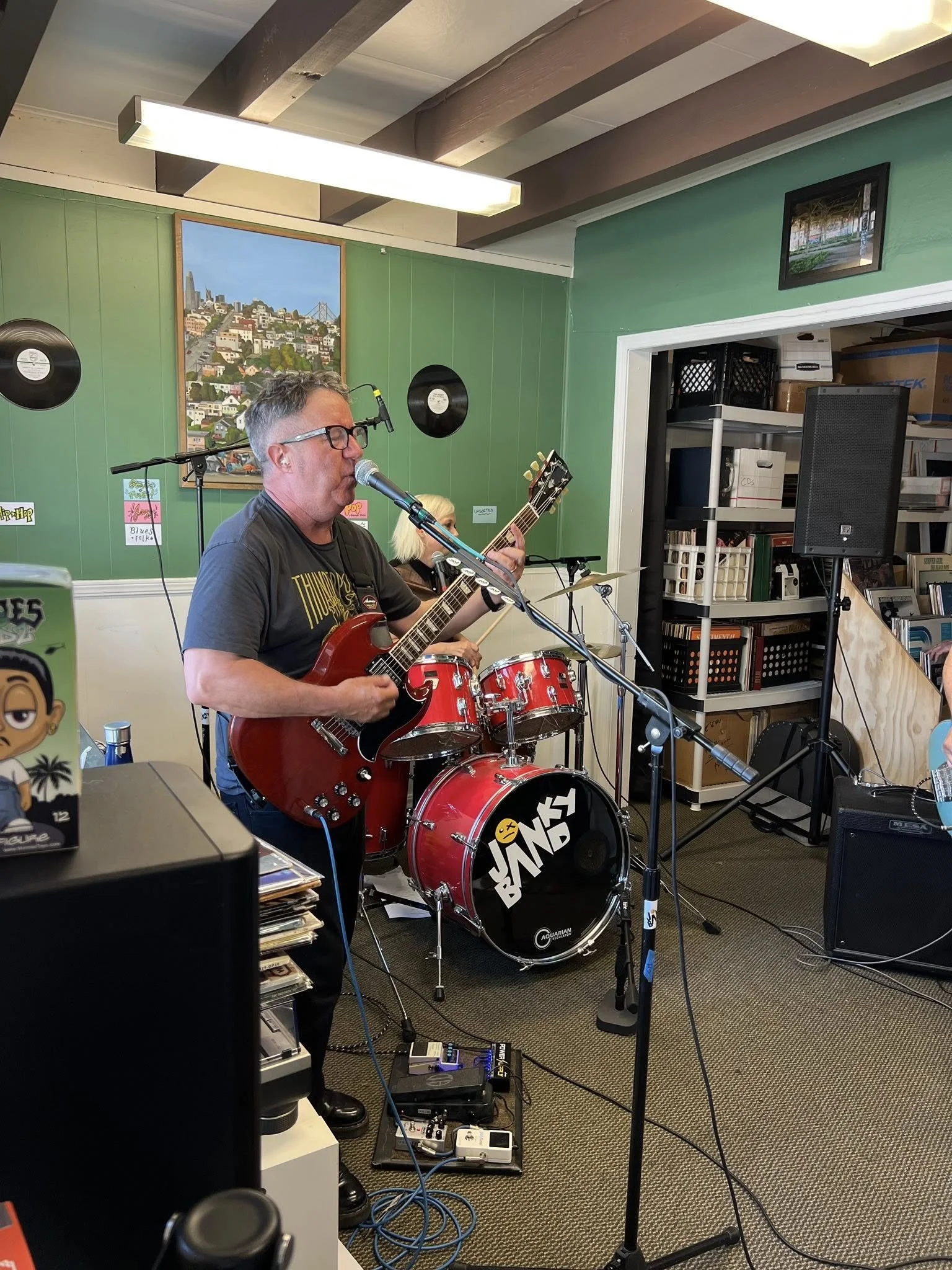 A guitarist and drummer perform inside the music space.