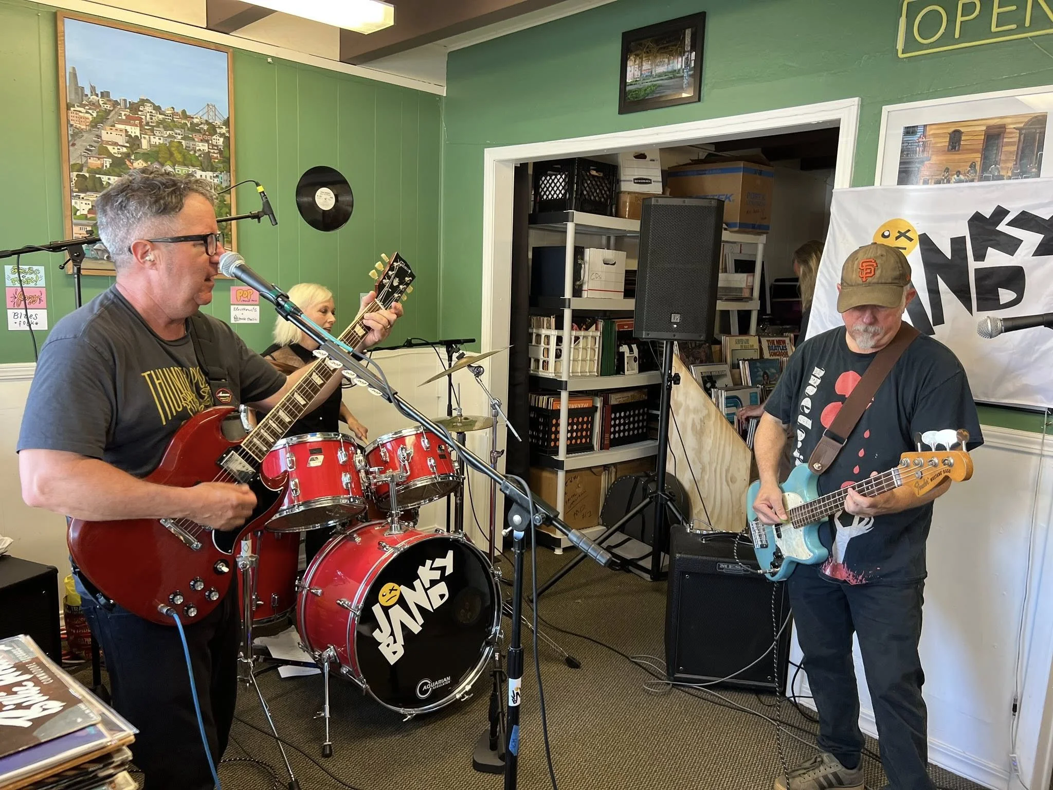 Two guitarists perform beside a drum kit.