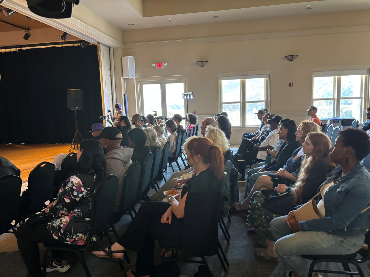 Audience members seated in a bright community hall.