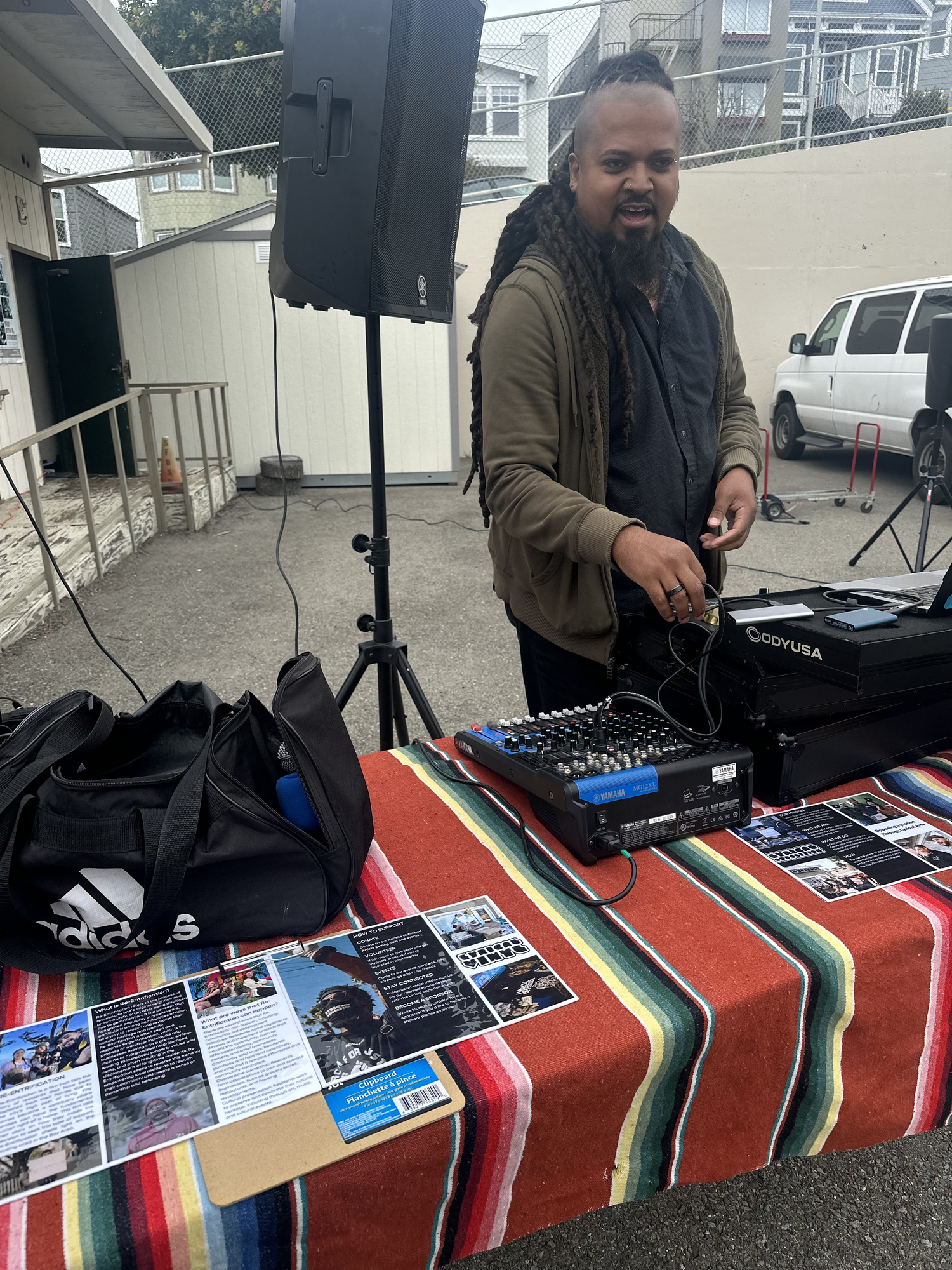 A DJ performs at a table covered with a striped cloth.