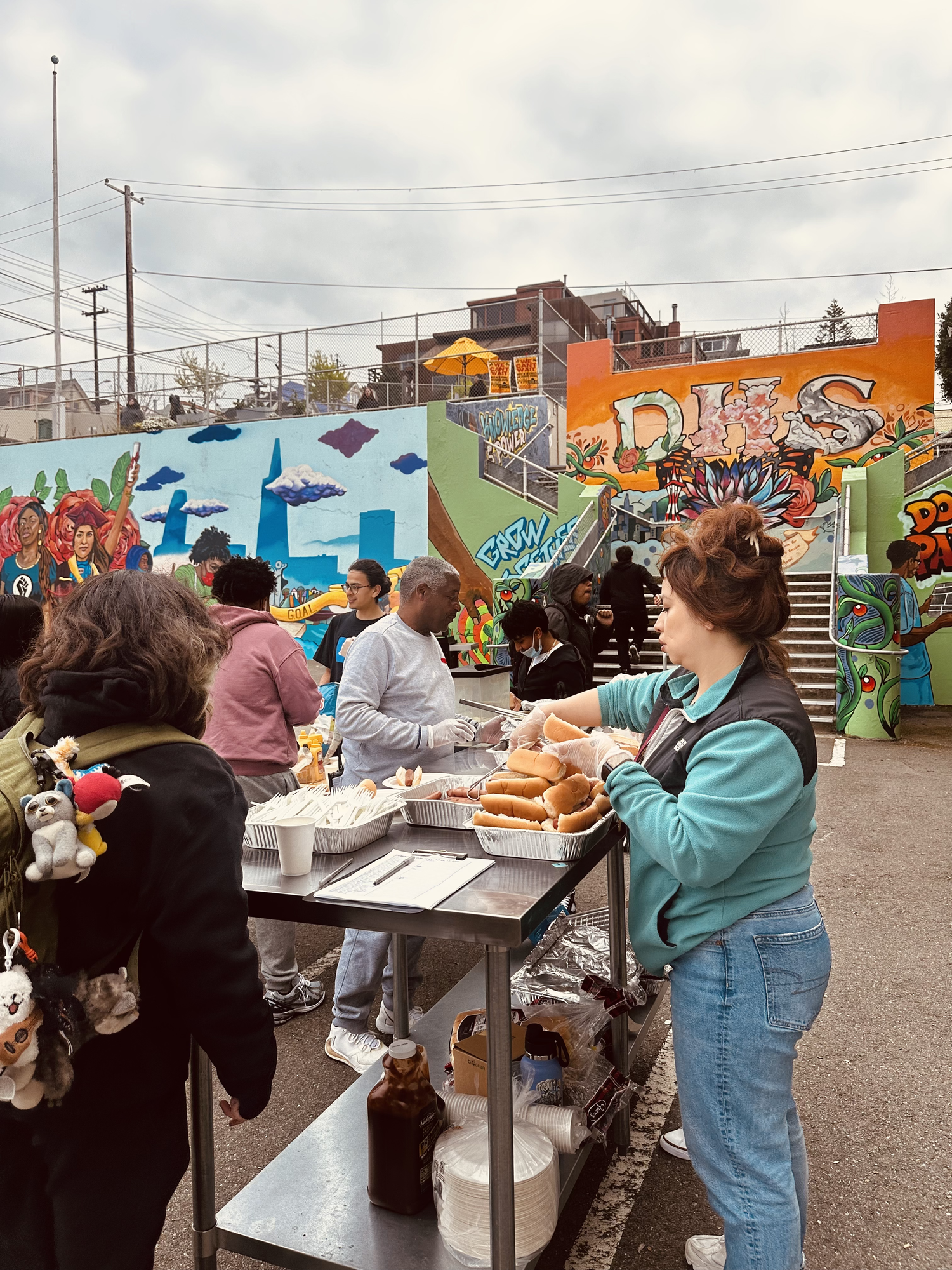Visitors gather beside community stalls and a mural.