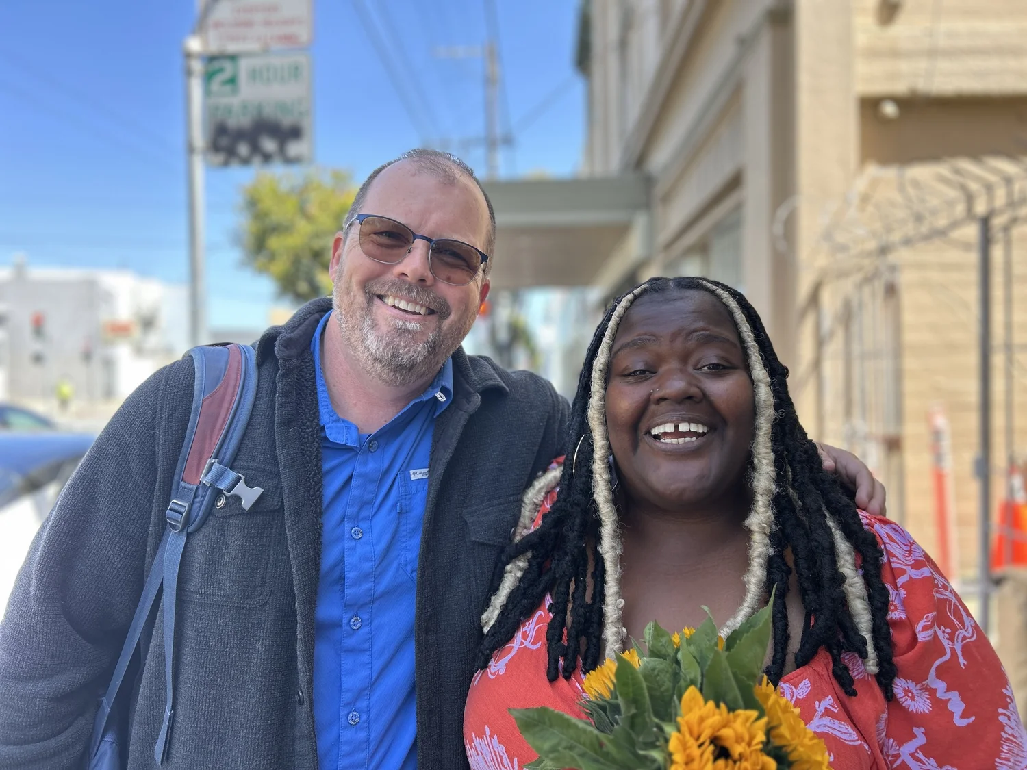 Two participants smile together outdoors.