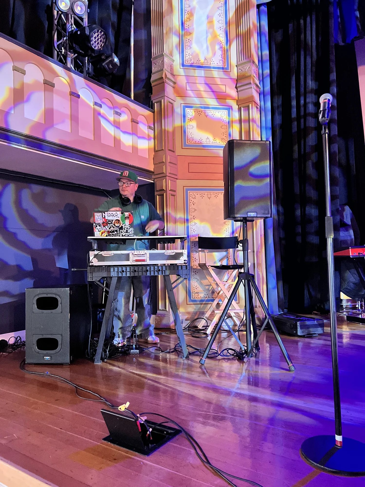 Keyboards and microphones on a colorfully lit stage.