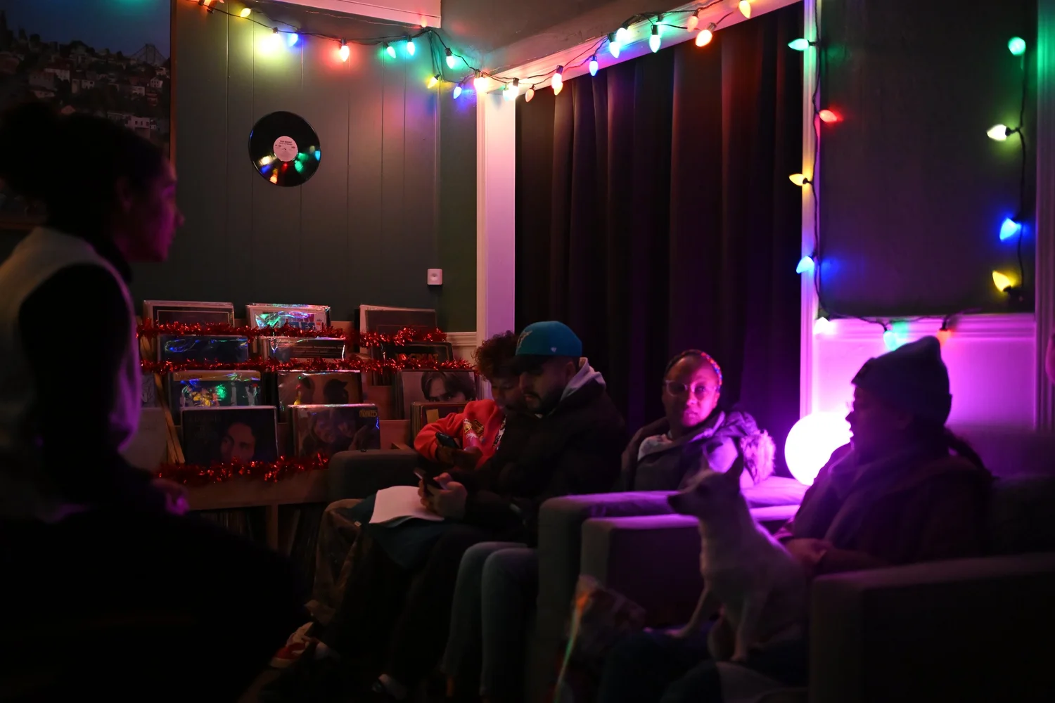 Guests sit together beneath colorful string lights.