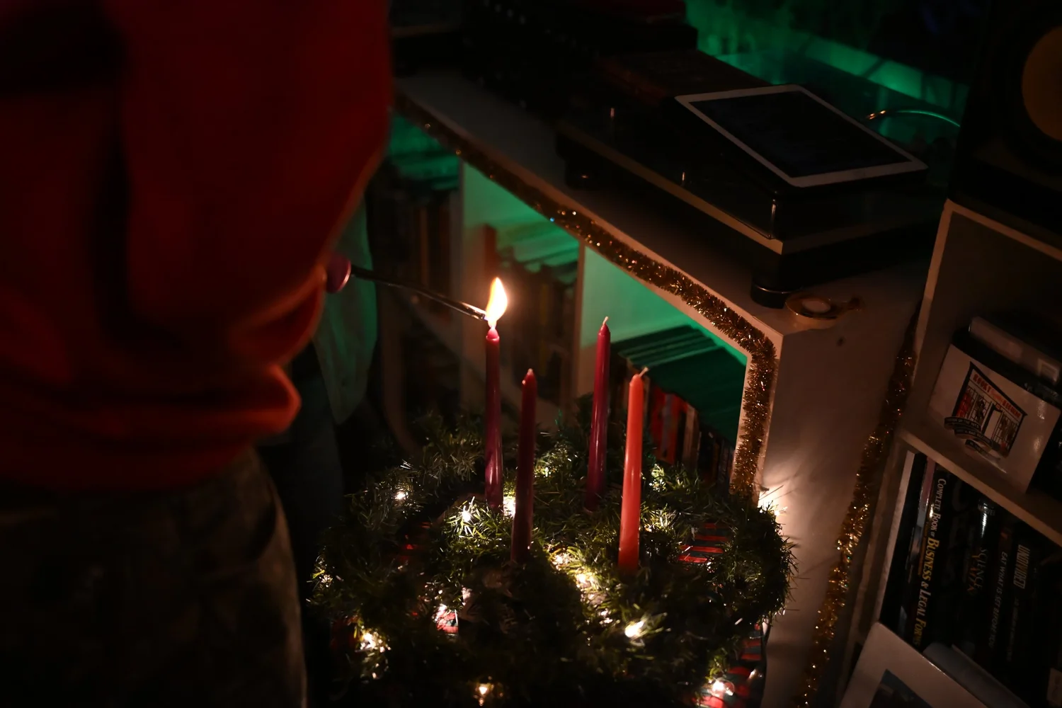 A candle burns in an Advent wreath beside records.