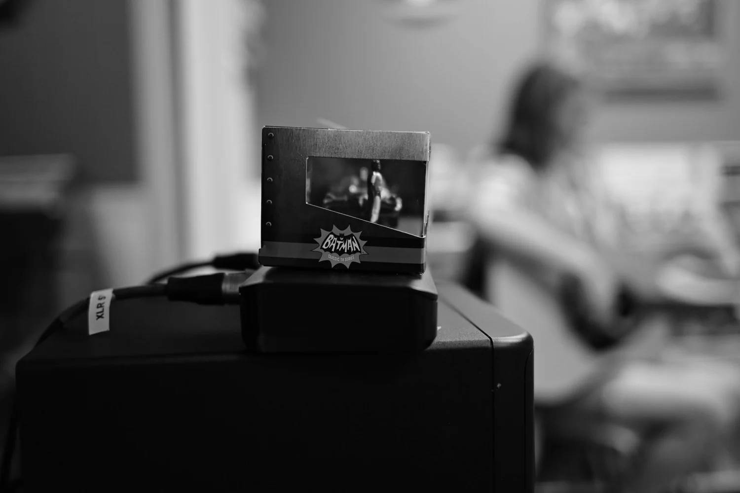 Small display device in focus with a musician blurred behind it.