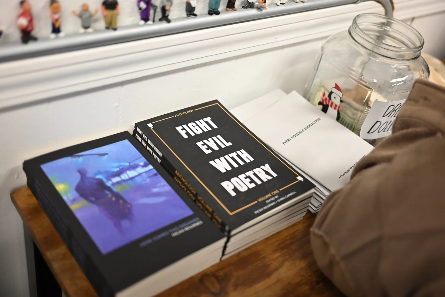 Books including Fight Evil with Poetry displayed beside a tablet.