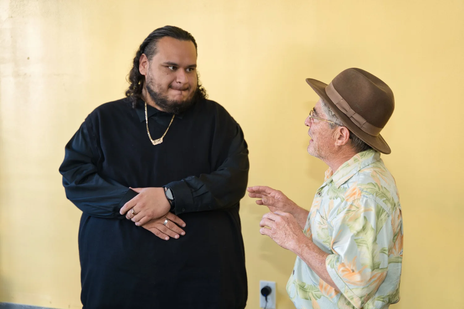 Two participants conversing against a yellow wall.